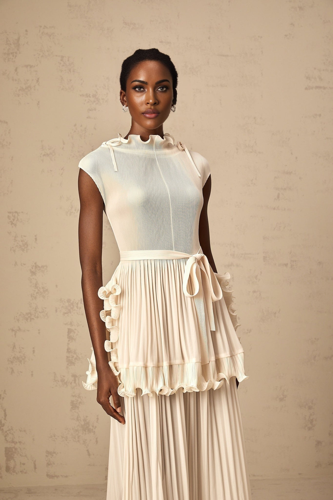 A long white sleeveless maxi dress with ruffles and pleats named Diana