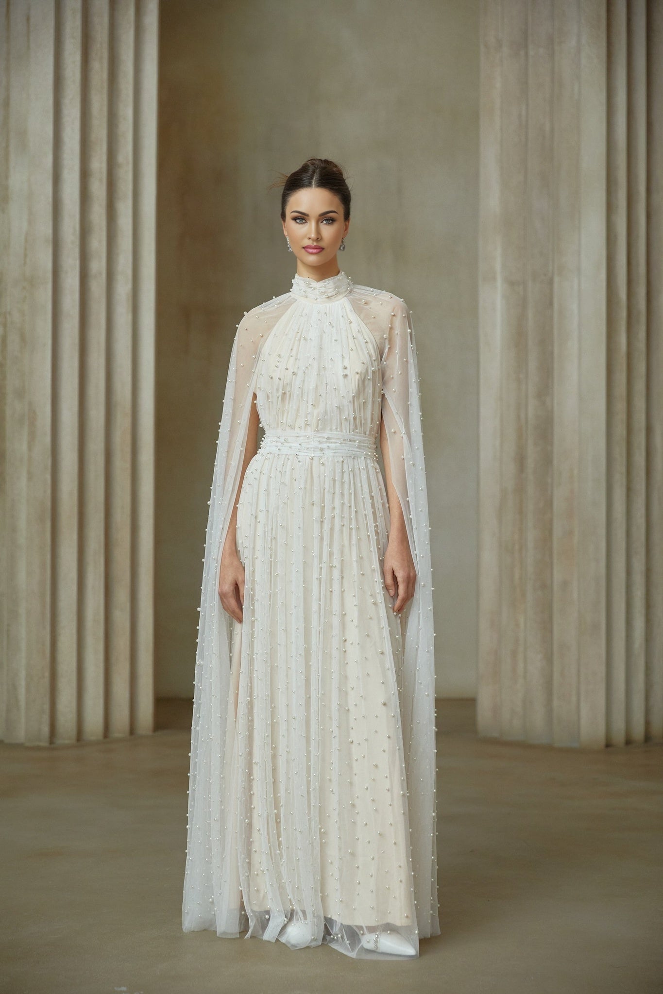 A long white tulle maxi dress with cape design and embellishments featuring a flowy silhouette and delicate detailing
