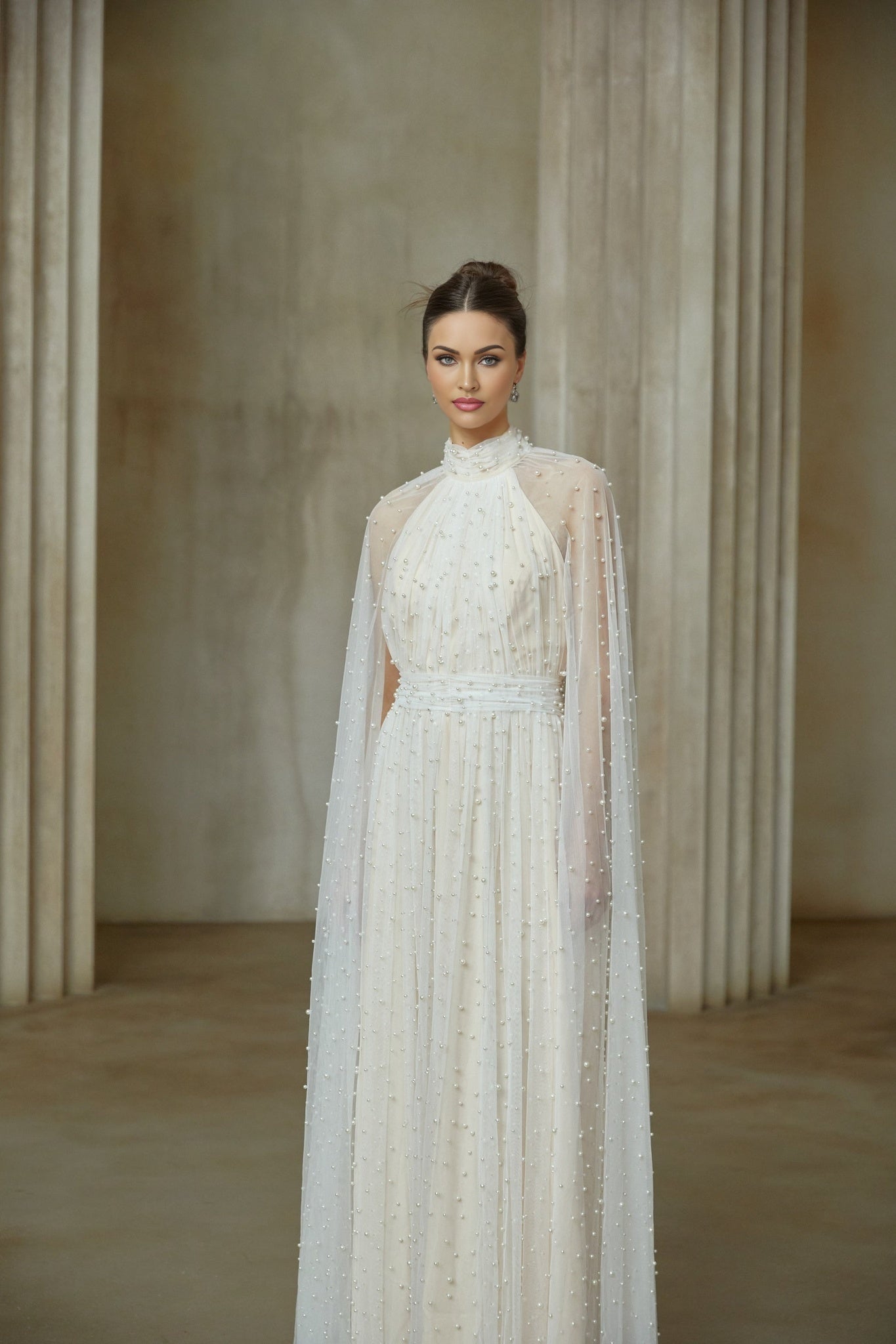 A long white tulle maxi dress with cape design and embellishments featuring a flowy silhouette and delicate details