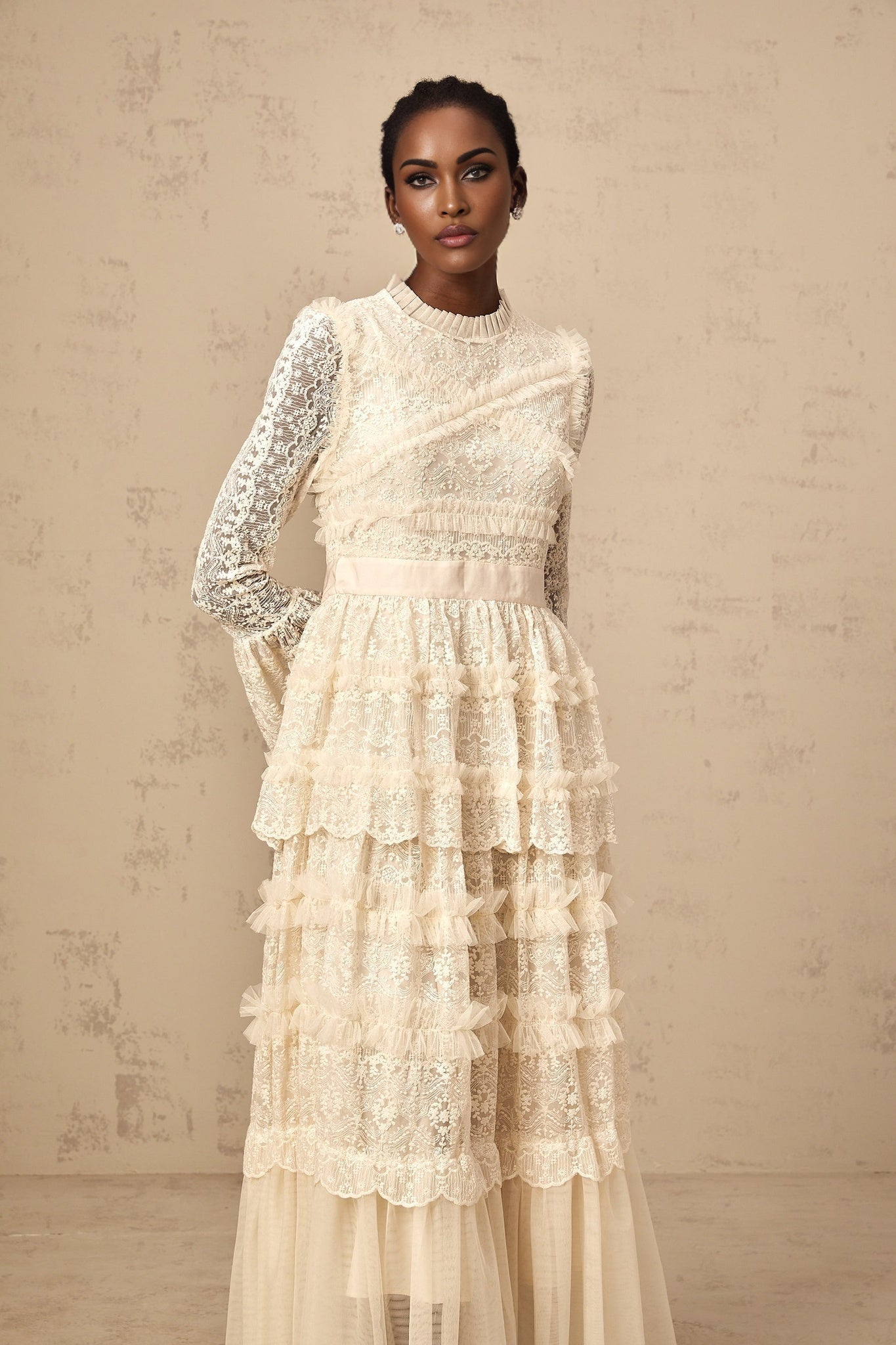A long white tulle maxi dress with lace panels and ruffled details featuring a romantic and ethereal design in neutral tones