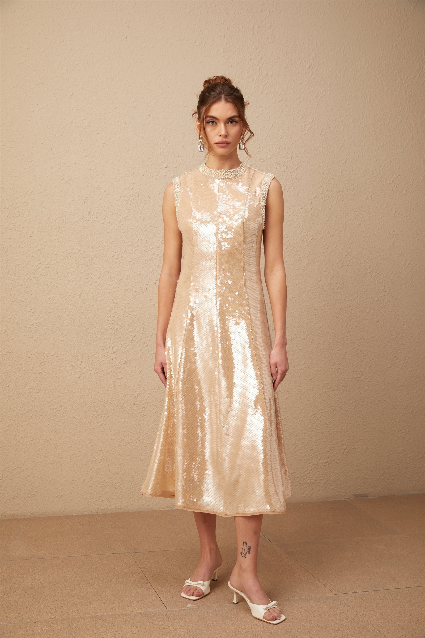 A midi length dress with sequin embellishments and faux pearl accents featuring a shimmering ornate design