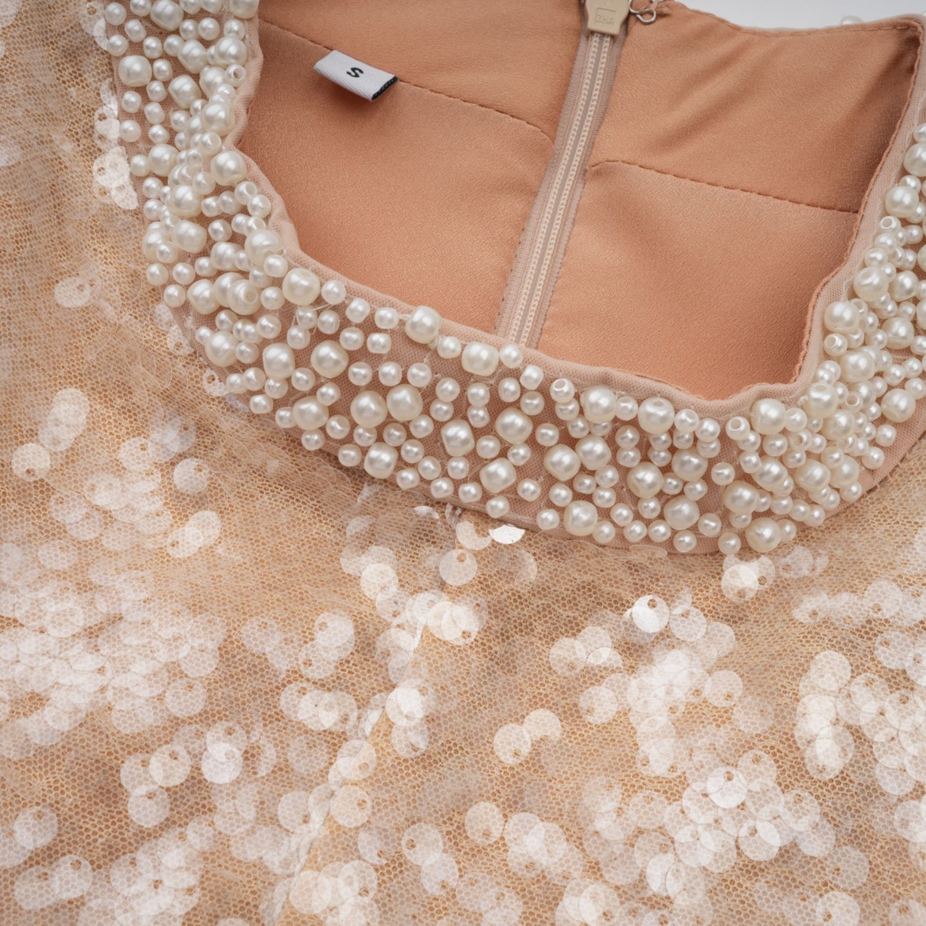 A midilength dress with sequin embellishments and faux pearl details adorning the fabric