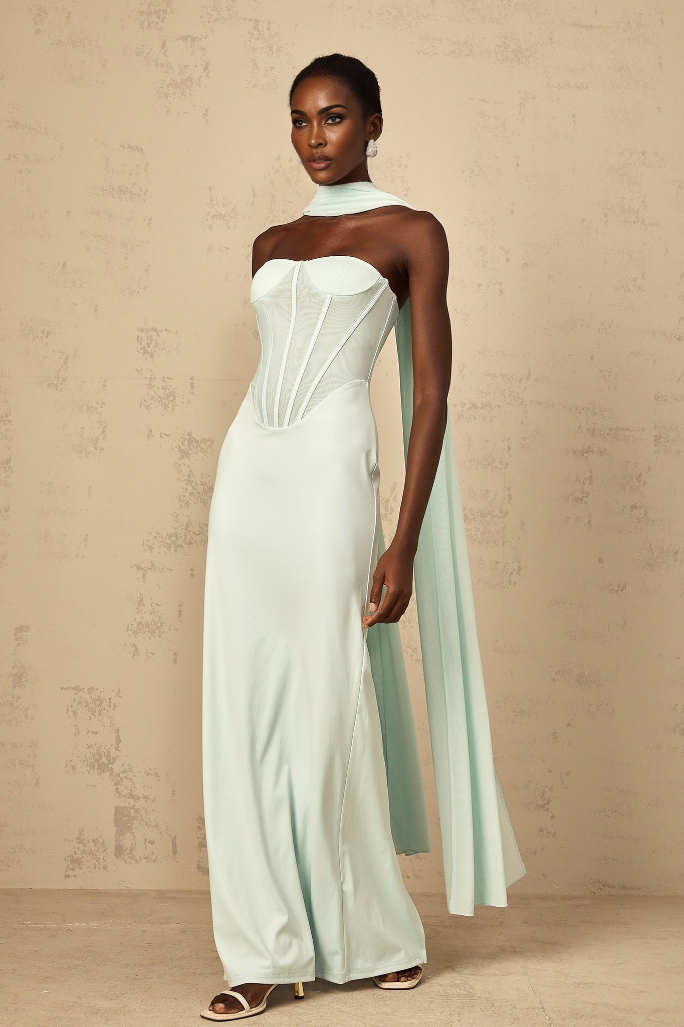 A mint green maxi dress with a corset bodice and sheer tulle panel details featuring a long flowy skirt and delicate Beryl inspired design