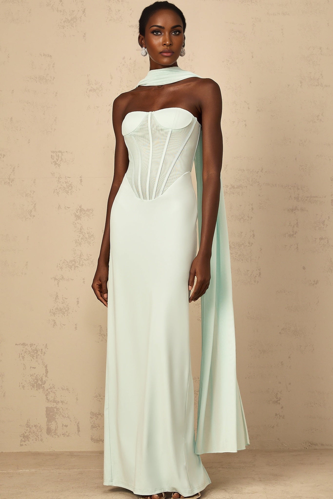 A mint green maxi dress with a corset bodice and tulle panel details featuring a long flowy skirt