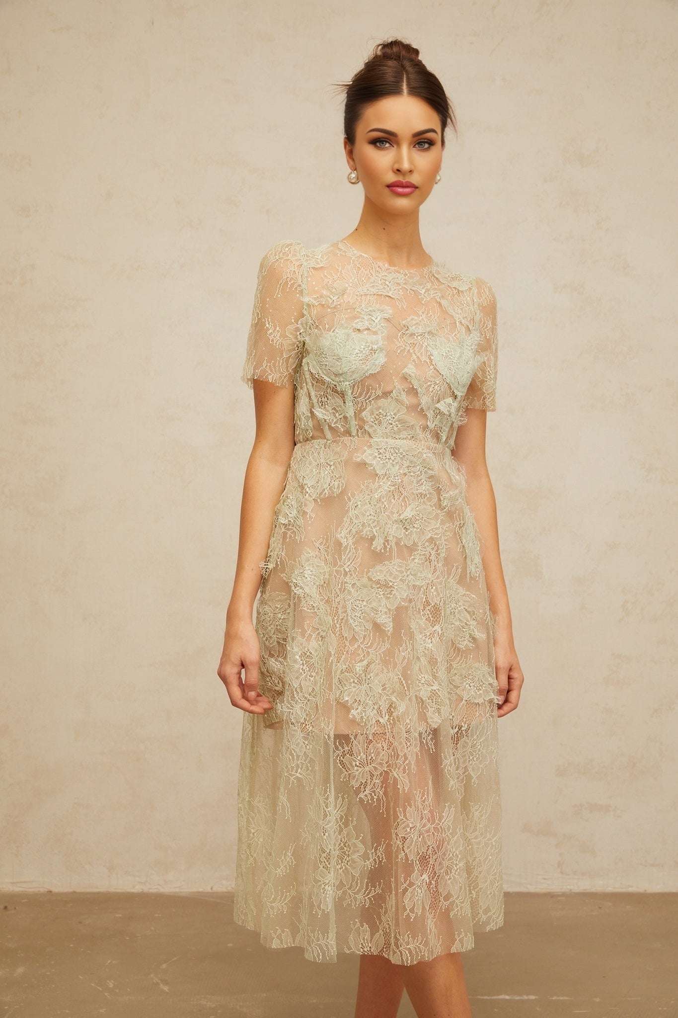 A mintgreen midi dress with floral lace pattern and a feminine silhouette
