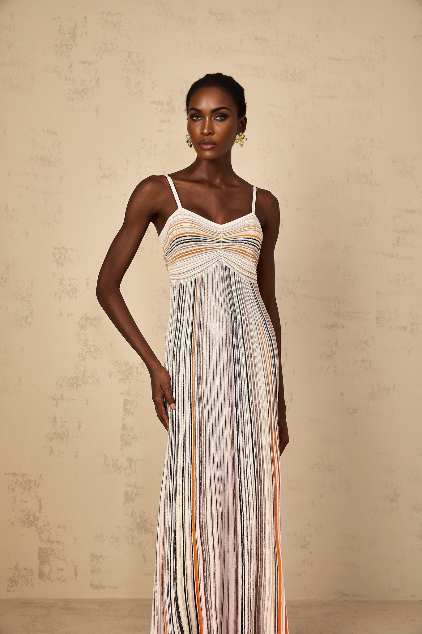 A neutral colored maxi dress with sequin stripes knitted into the fabric featuring long sleeves and a floor length silhouette