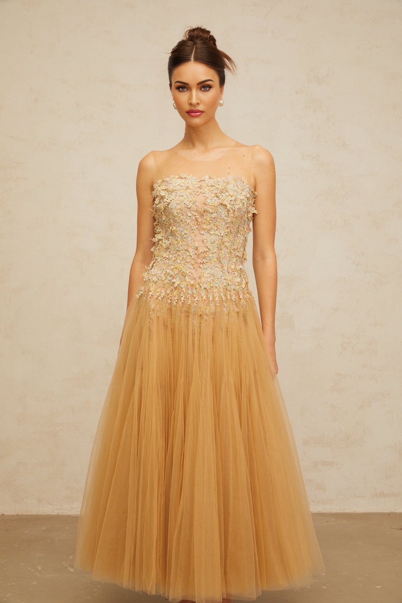 A neutral colored midi dress with pleated tulle fabric and sequin embellishments featuring a sleeveless design and flowy silhouette
