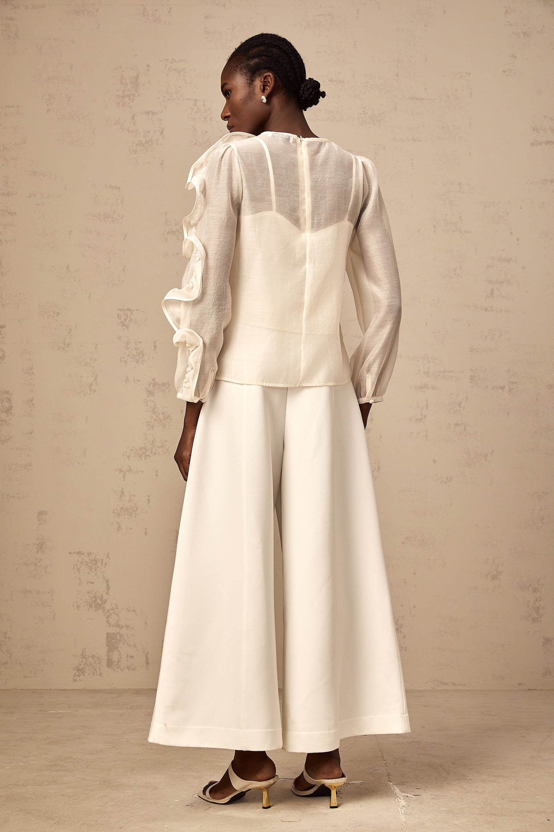 A neutralcolored blouse with delicate threedimensional flower details on sheer fabric creating a soft and feminine appearance