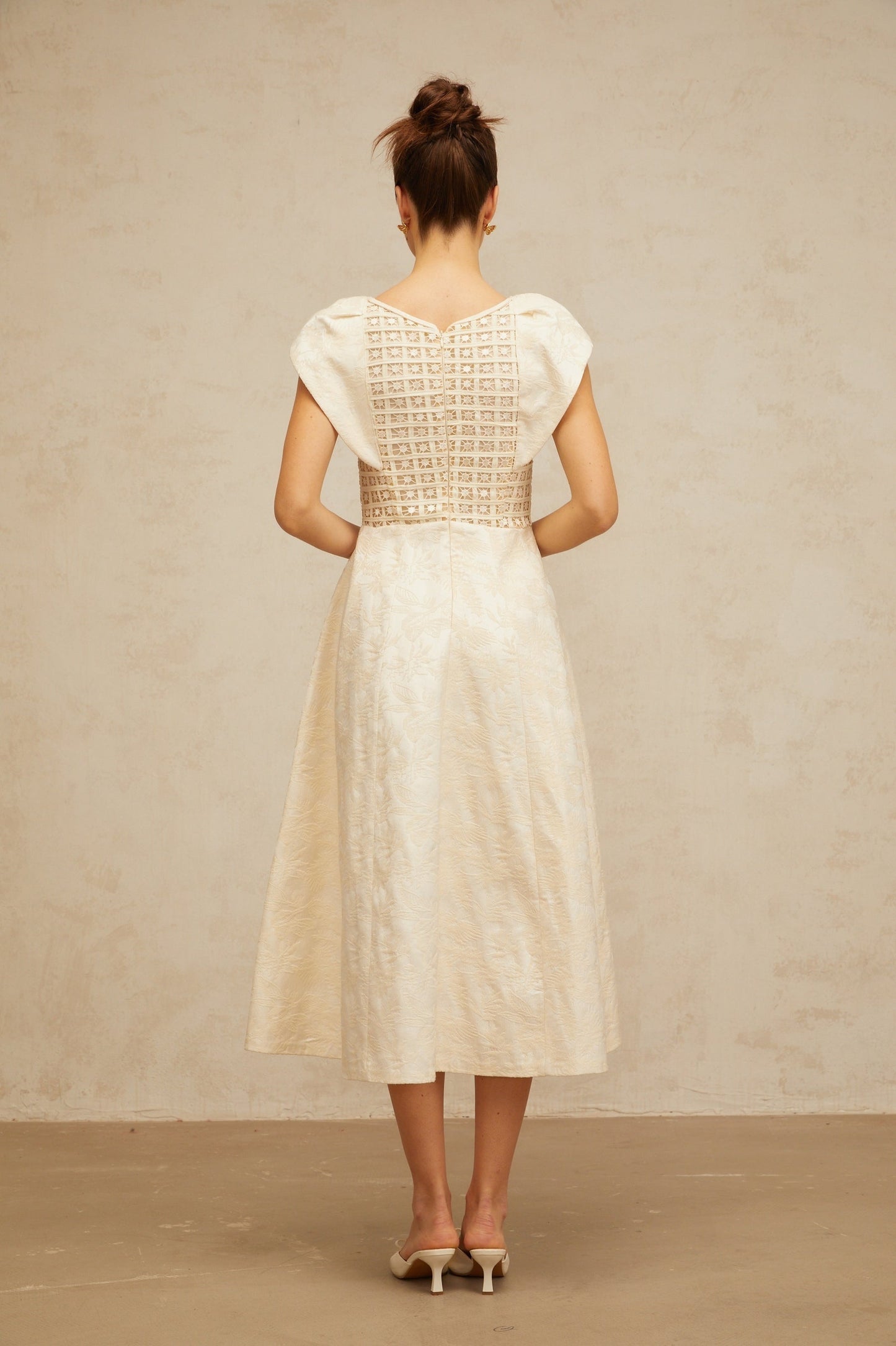 A neutralcolored midi dress with floral embroidery and embellishments featuring the Xenia brand design