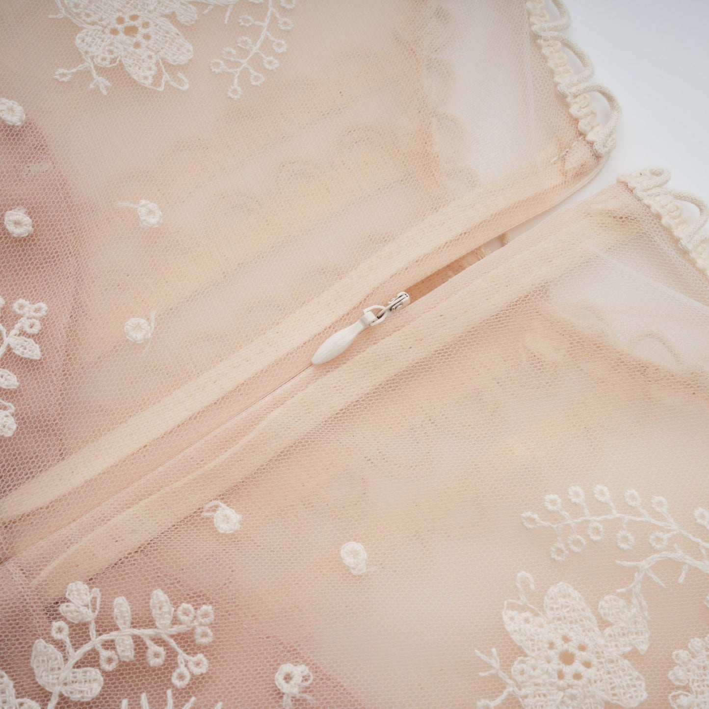 A neutralcolored midi dress with floral embroidery and lace details featuring a delicate fleur pattern