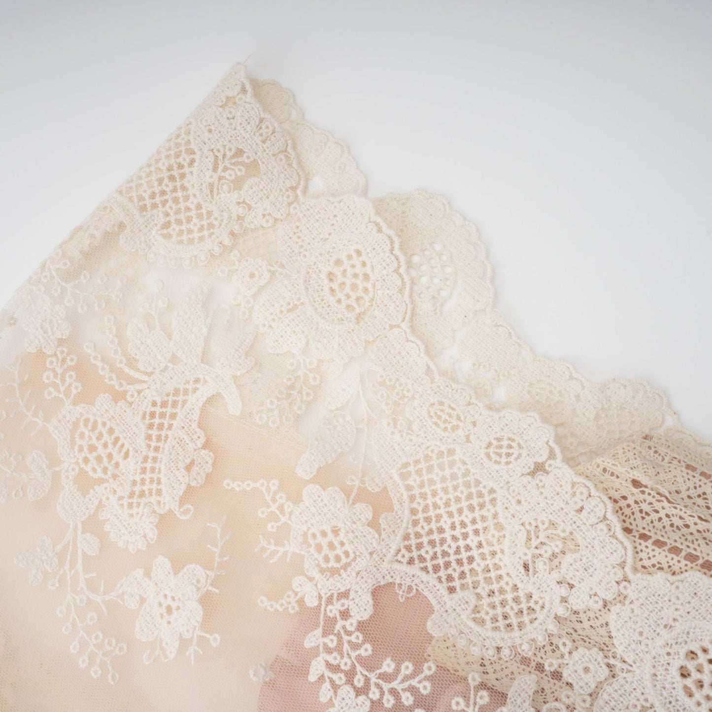 A neutralcolored midi dress with floral embroidery and lace details featuring a delicate fleur pattern