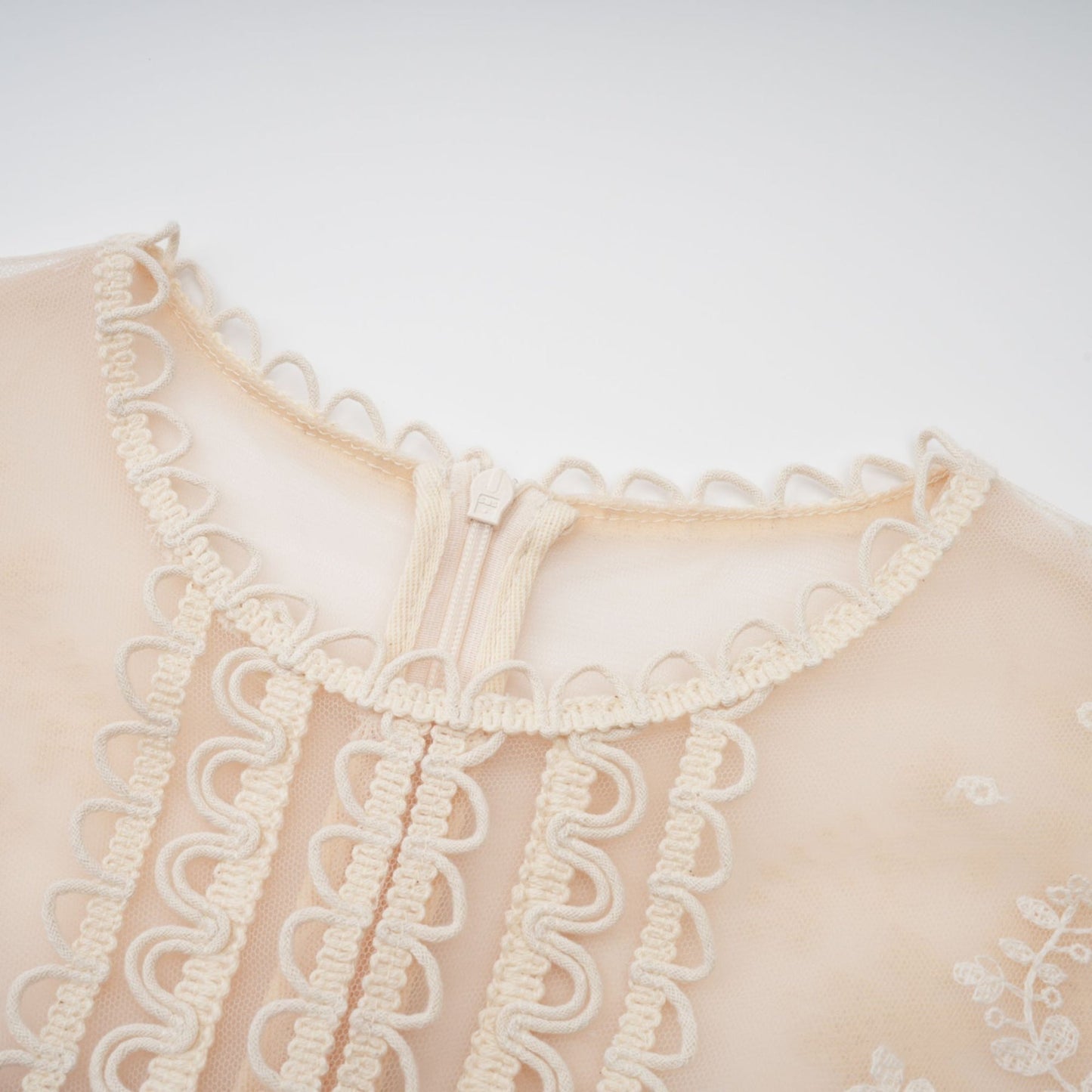 A neutralcolored midi dress with floral embroidery and lace details featuring a delicate fleur pattern