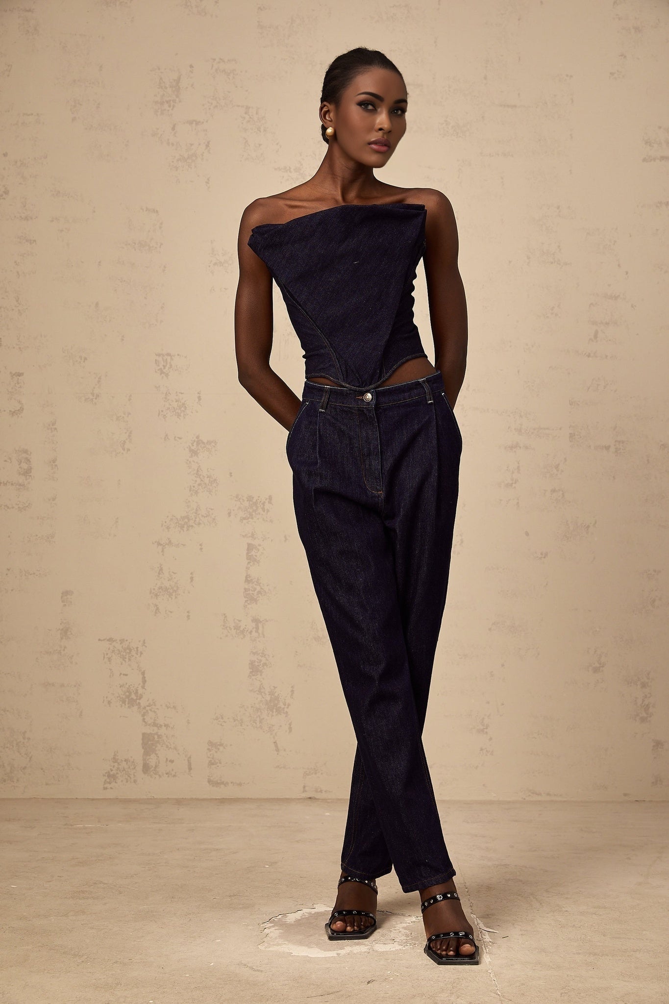 A pair of blue high rise jeans with pleated details on the front named Danae