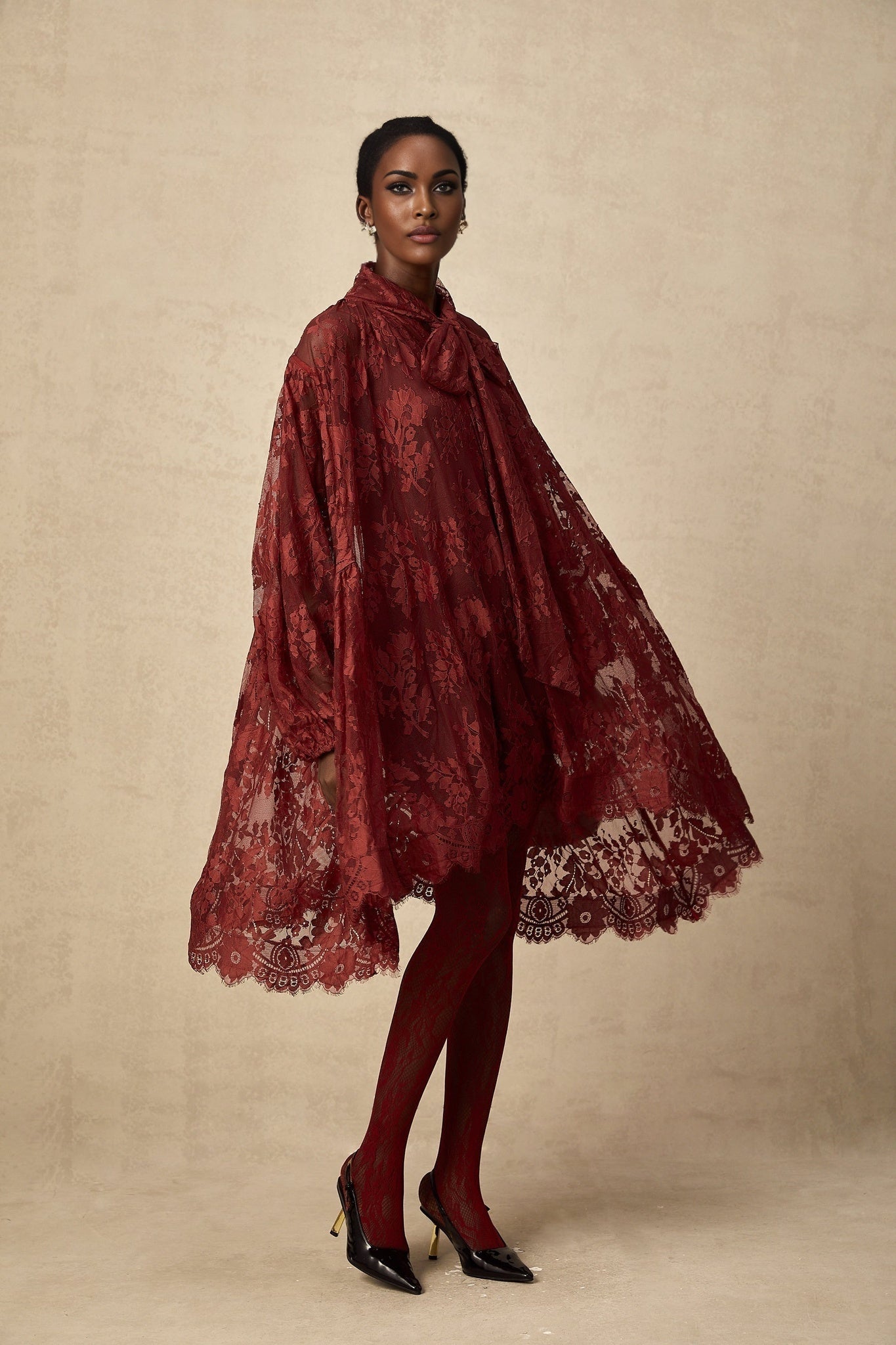 A pair of red tights with floral lace cutout patterns worn on a model showing the legs