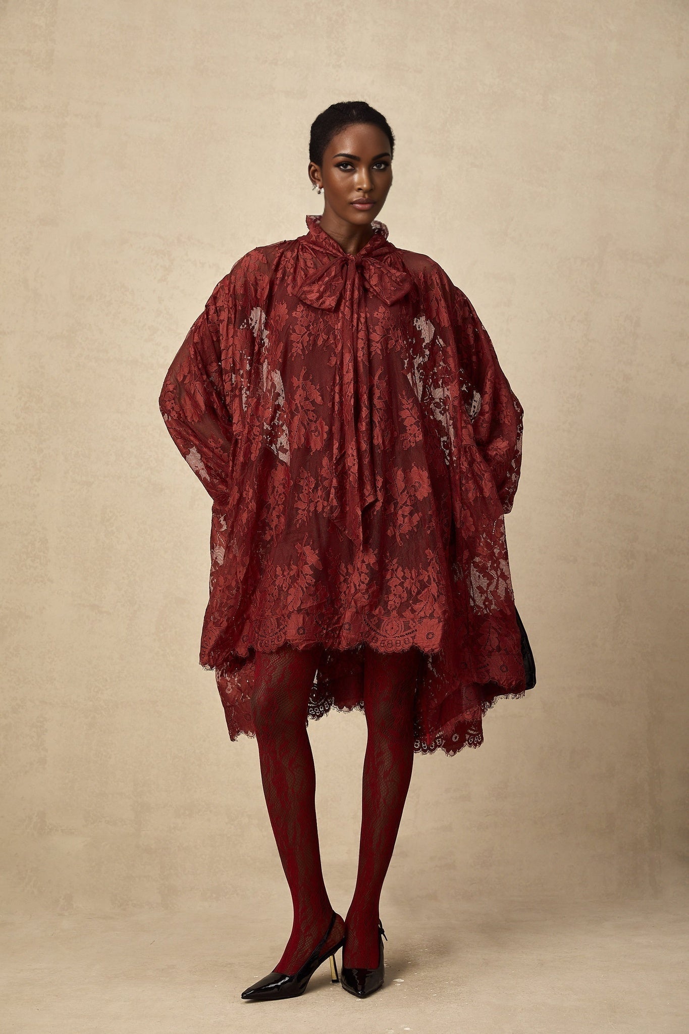 A pair of red tights with floral lace pattern and cut out details on display