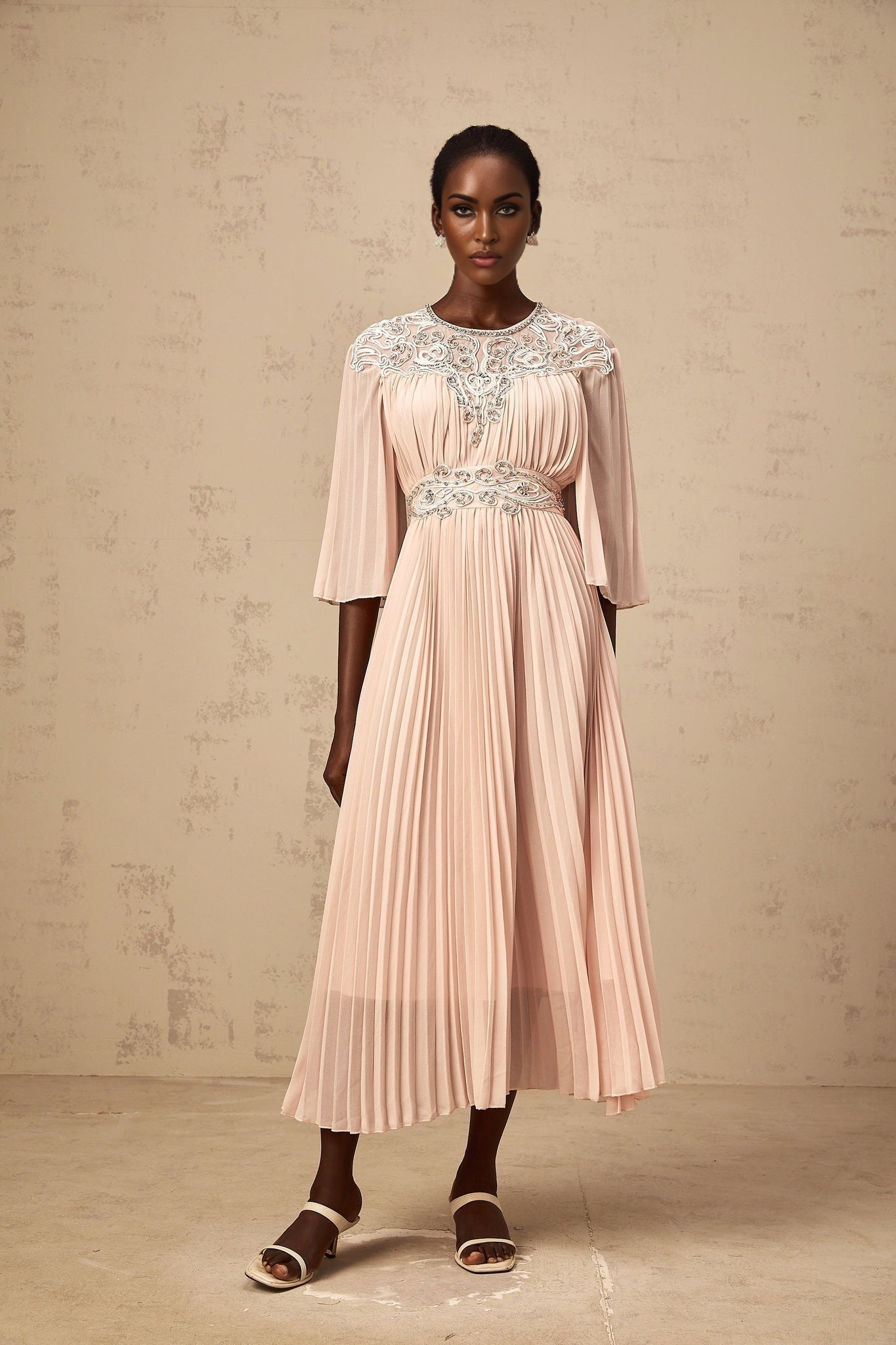 A pink crystal embellished midi dress with full pleats and a flowing silhouette