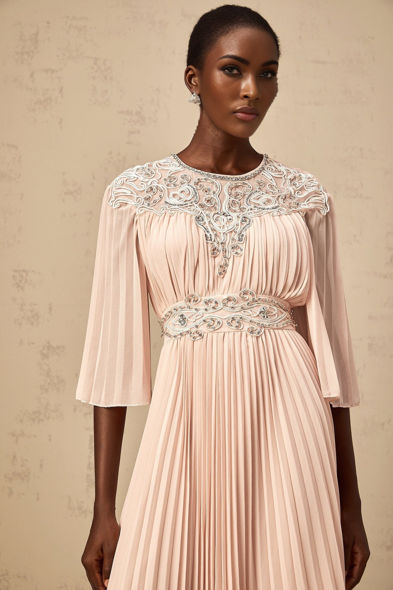 A pink crystal embellished midi dress with full pleats and a flowing skirt