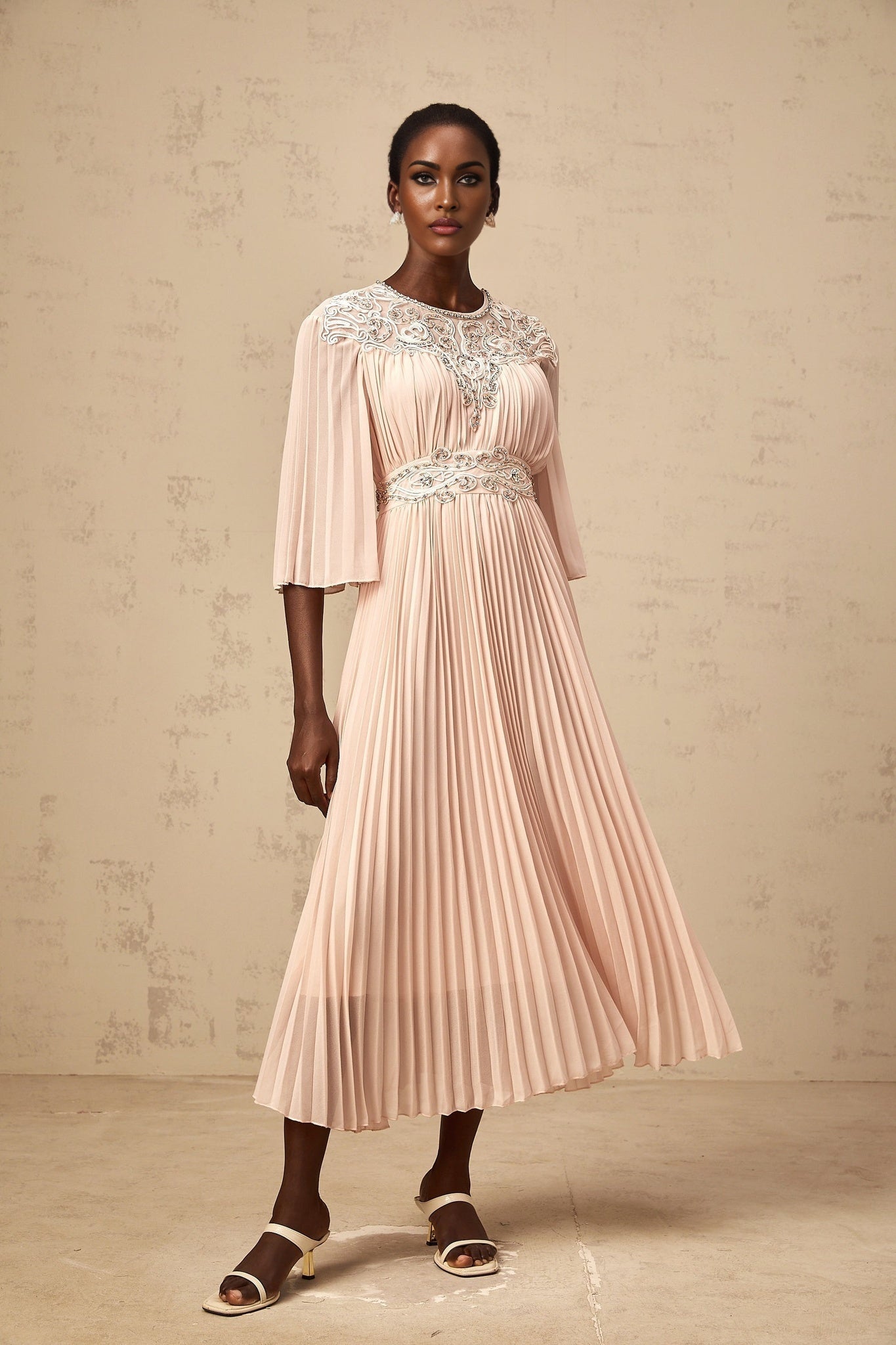 A pink crystal embellished midi dress with full pleats and a flowy silhouette