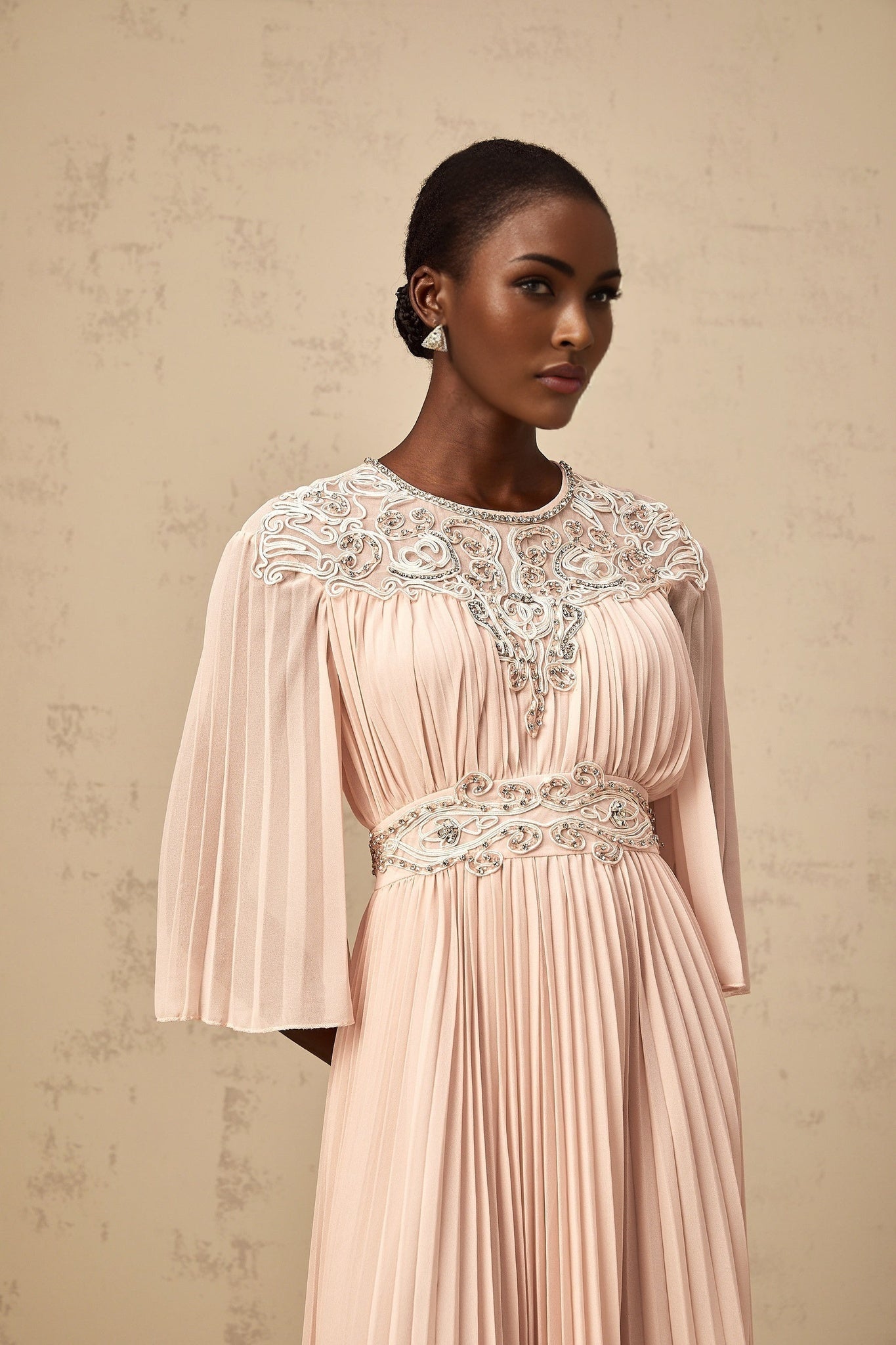 A pink crystal embellished midi dress with full pleats and a flowy silhouette