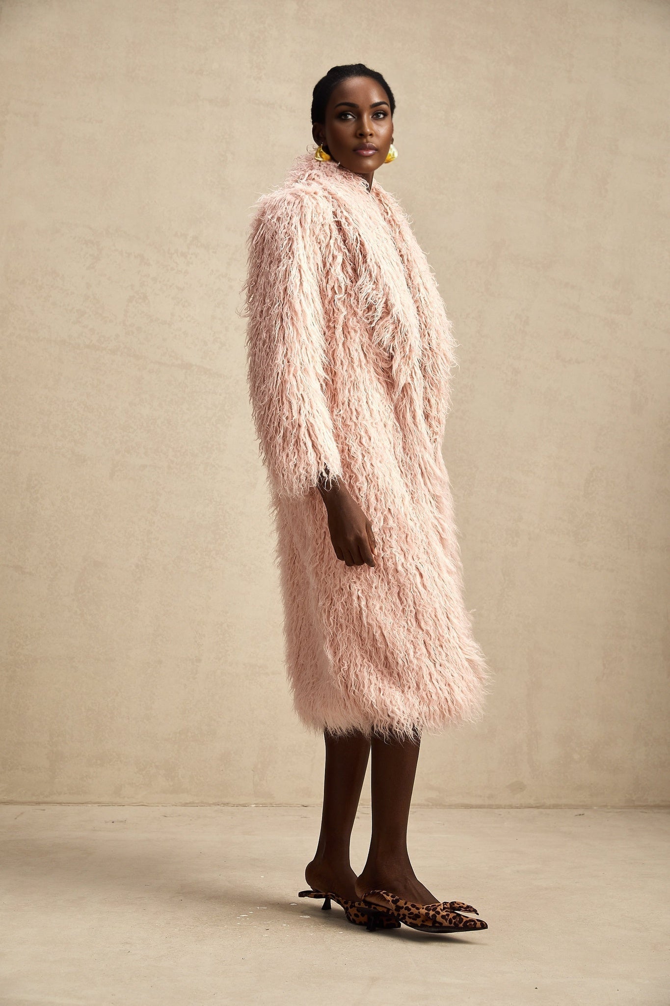 A pink faux fur coat with an open front design modeled by a woman
