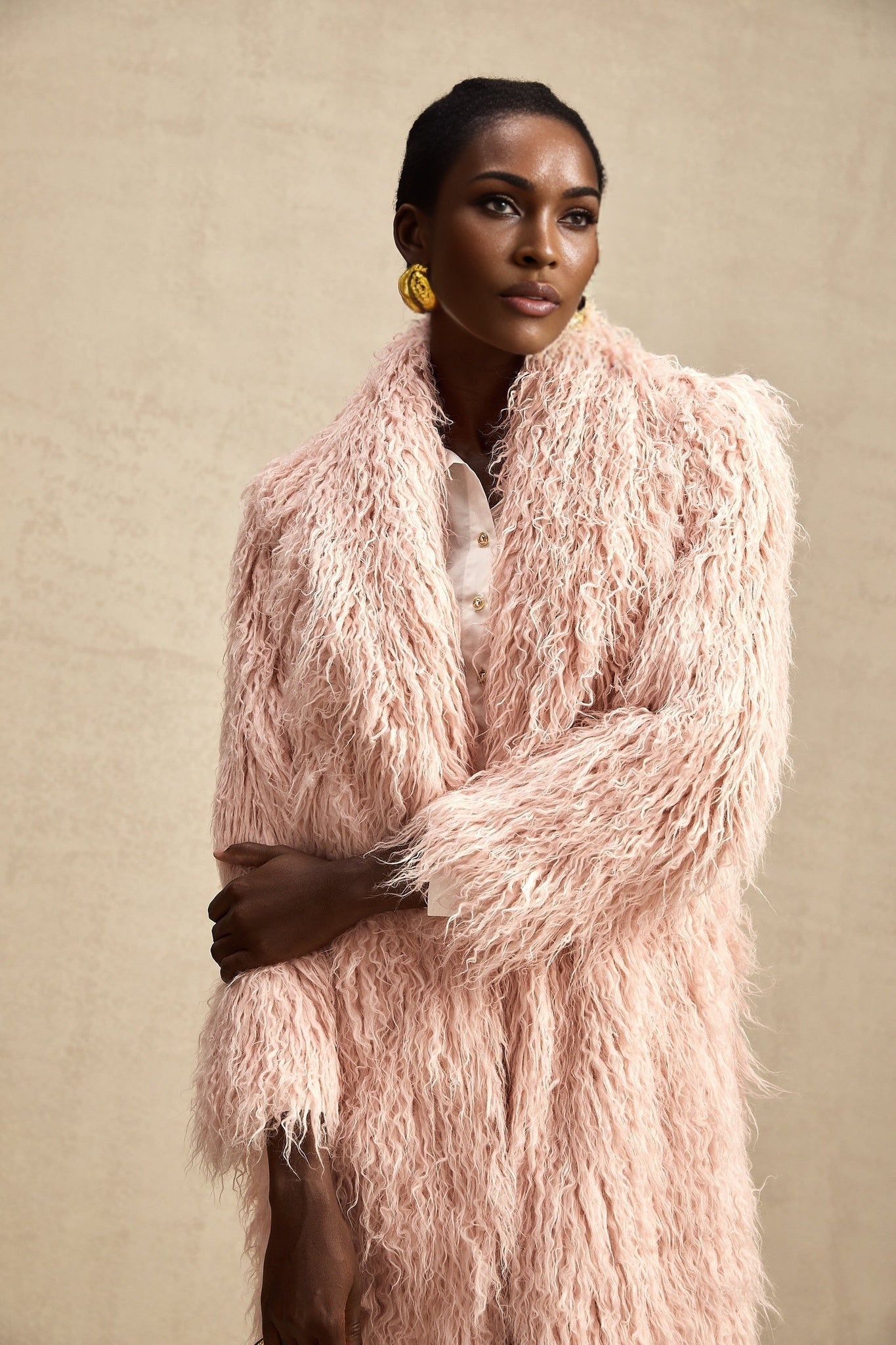 A pink faux fur coat with an open front design modeled by a woman