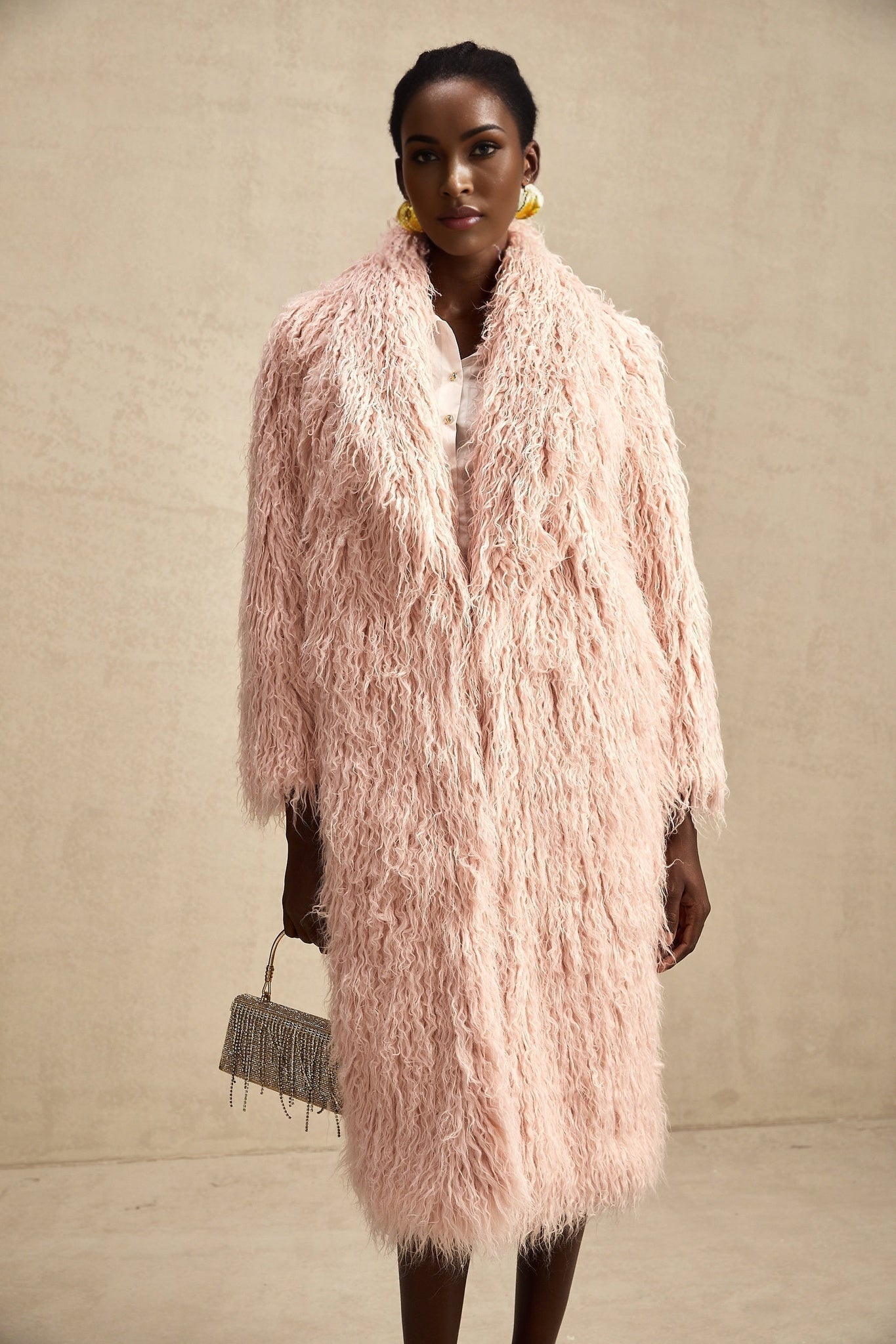 A pink faux fur coat with an open front design worn by a model against a plain background