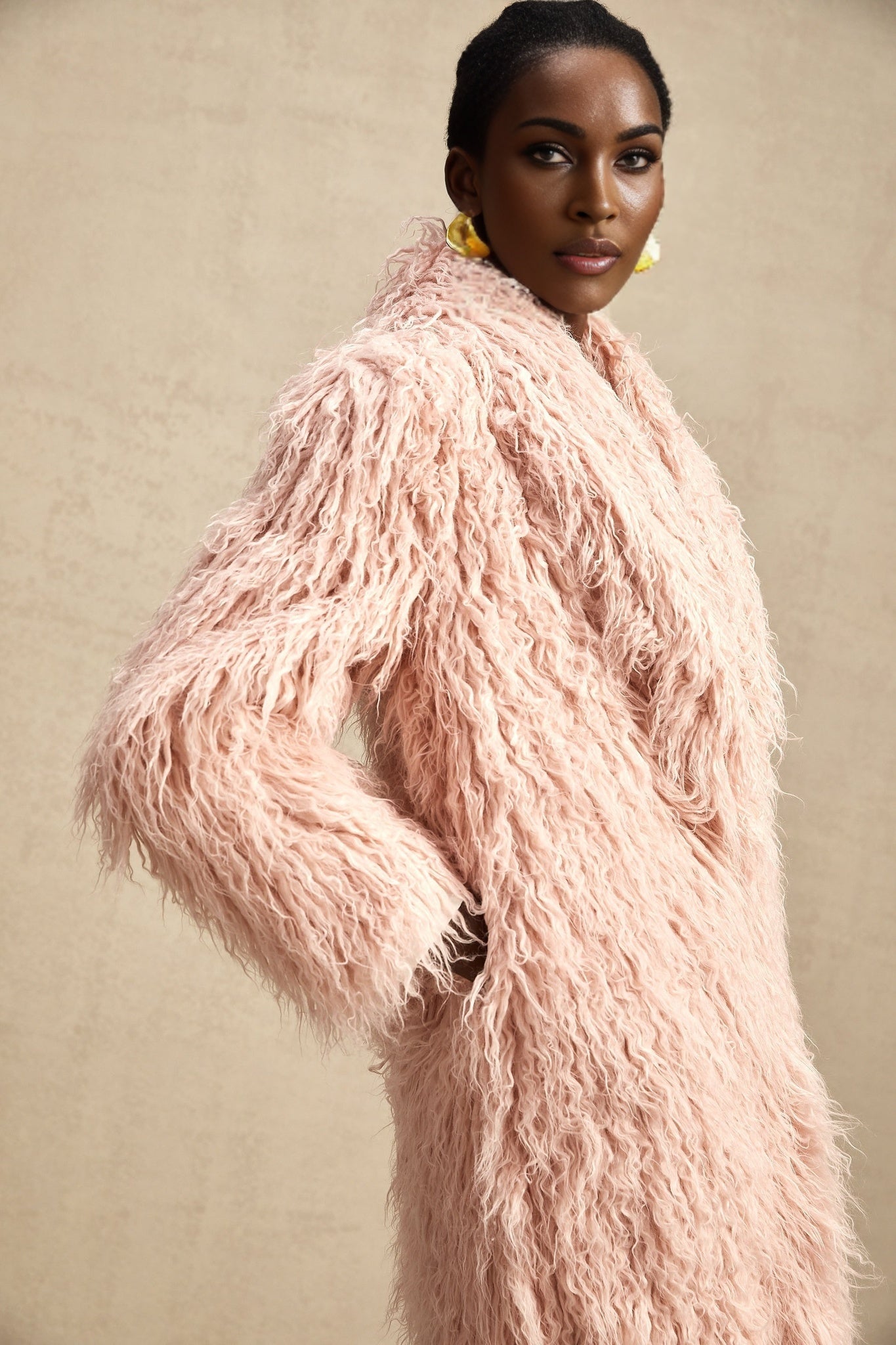 A pink faux fur coat with an open front design worn by a model named Melanie