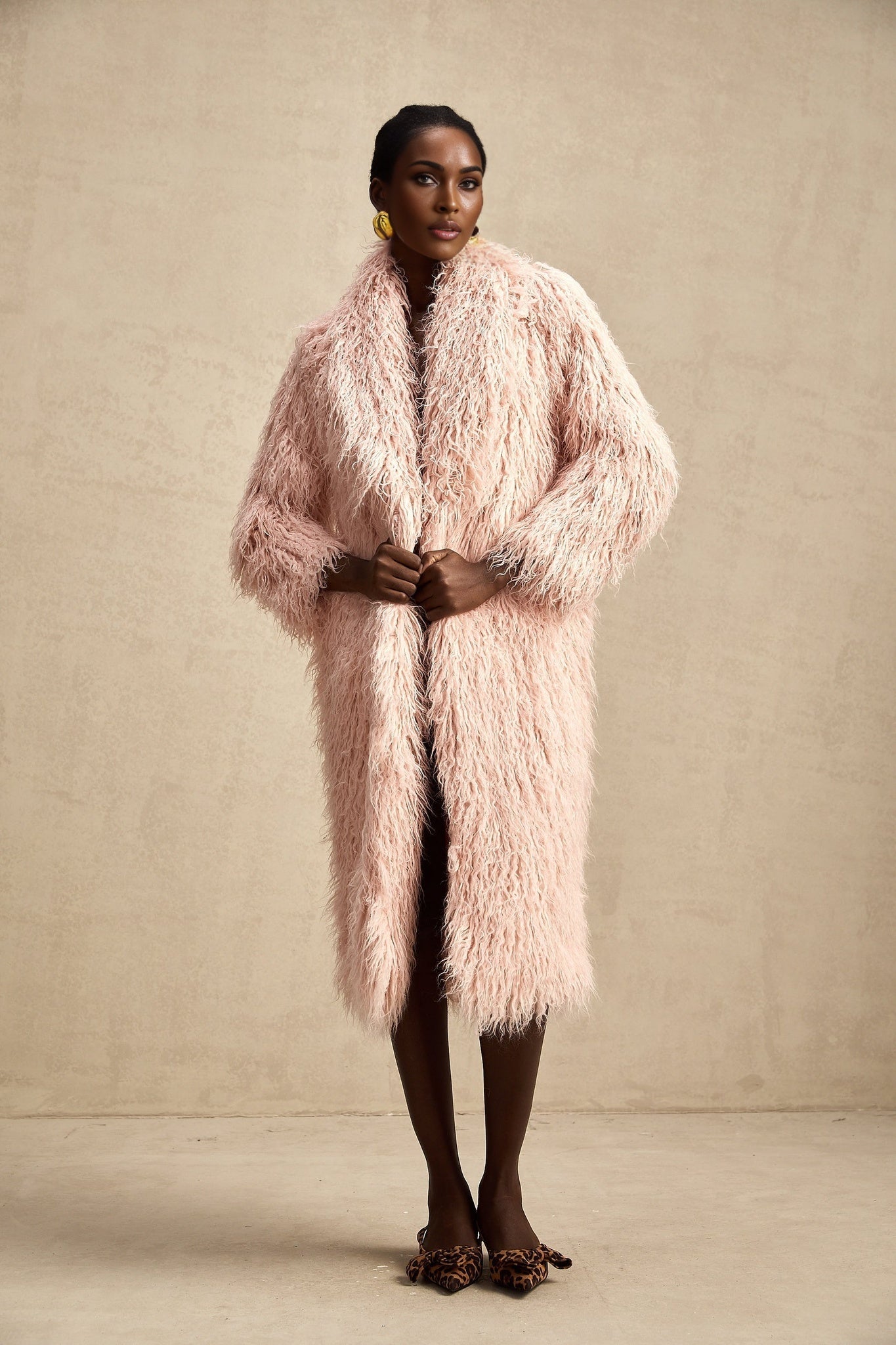 A pink faux fur coat with an open front design worn by a model
