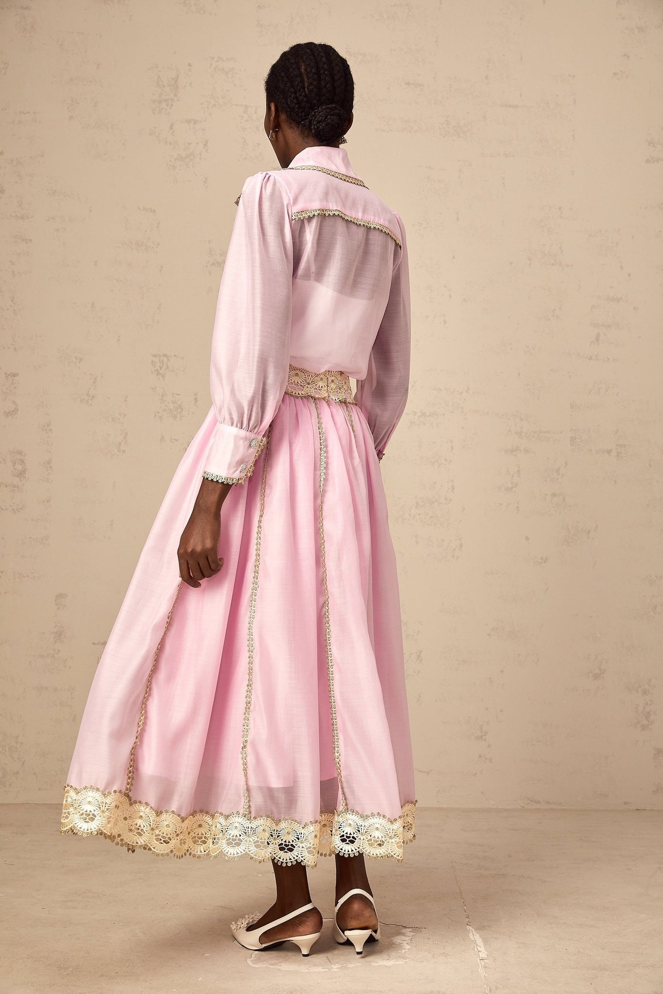 A pink matching set consisting of a lacetrimmed shirt and skirt from Frida The shirt and skirt are coordinated in style and color creating a cohesive outfit