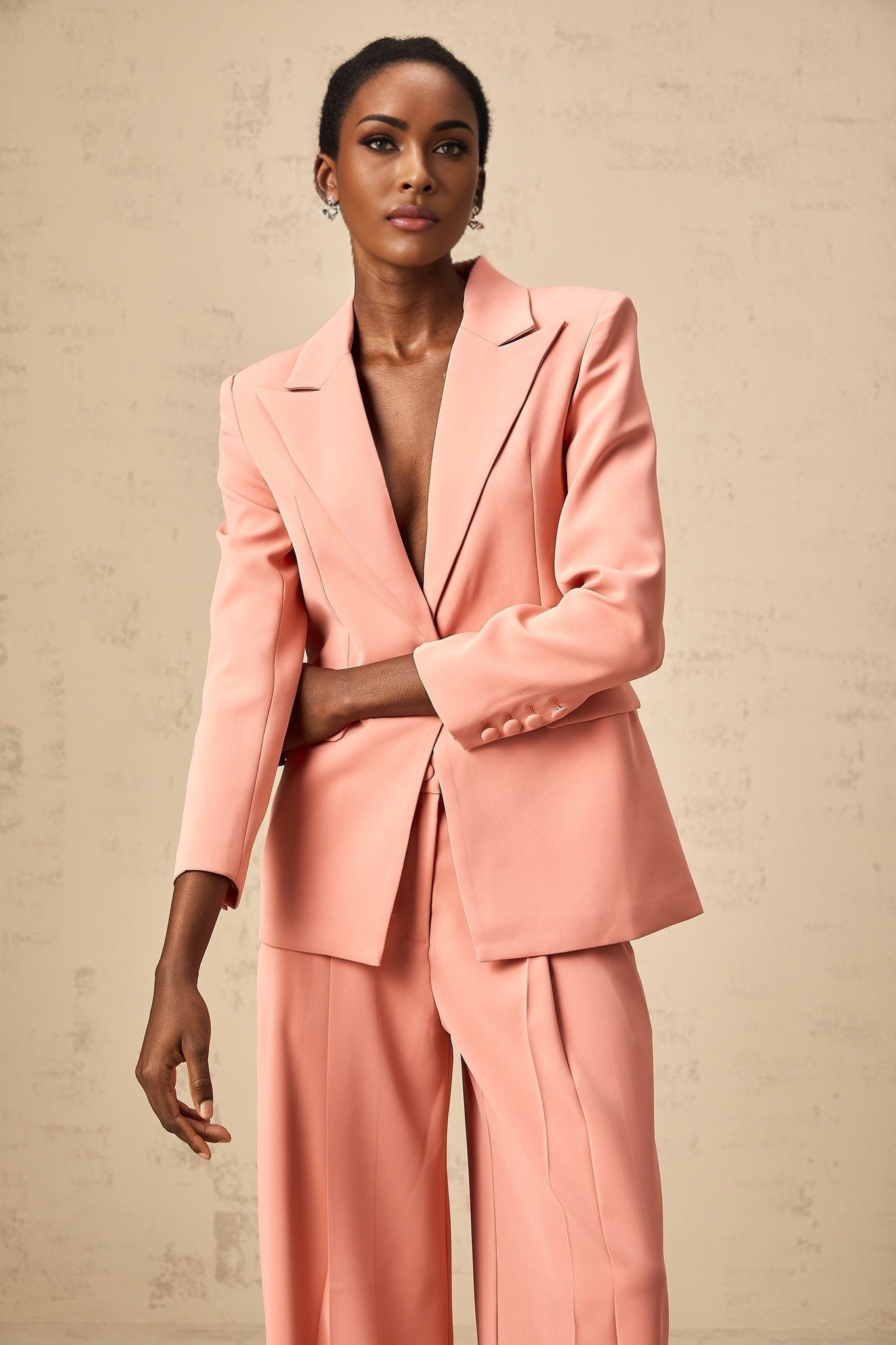 A pink matching set featuring a blazer and trousers with embroidery details and cutout design The blazer has a tailored fit while the trousers are sleek Both pieces showcase intricate embroidery work and strategically placed cutouts for a modern feminine look