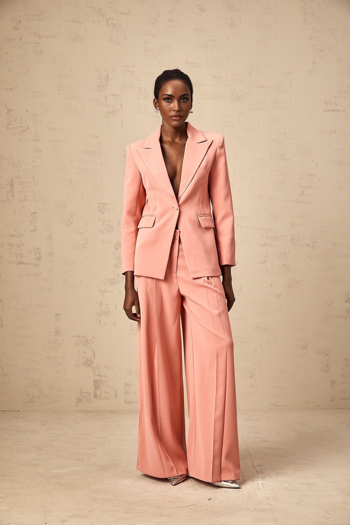 A pink matching set featuring a blazer and trousers with embroidery details and cutout designs The blazer has long sleeves and the trousers are full length Both pieces have a tailored fit and coordinating embroidery patterns