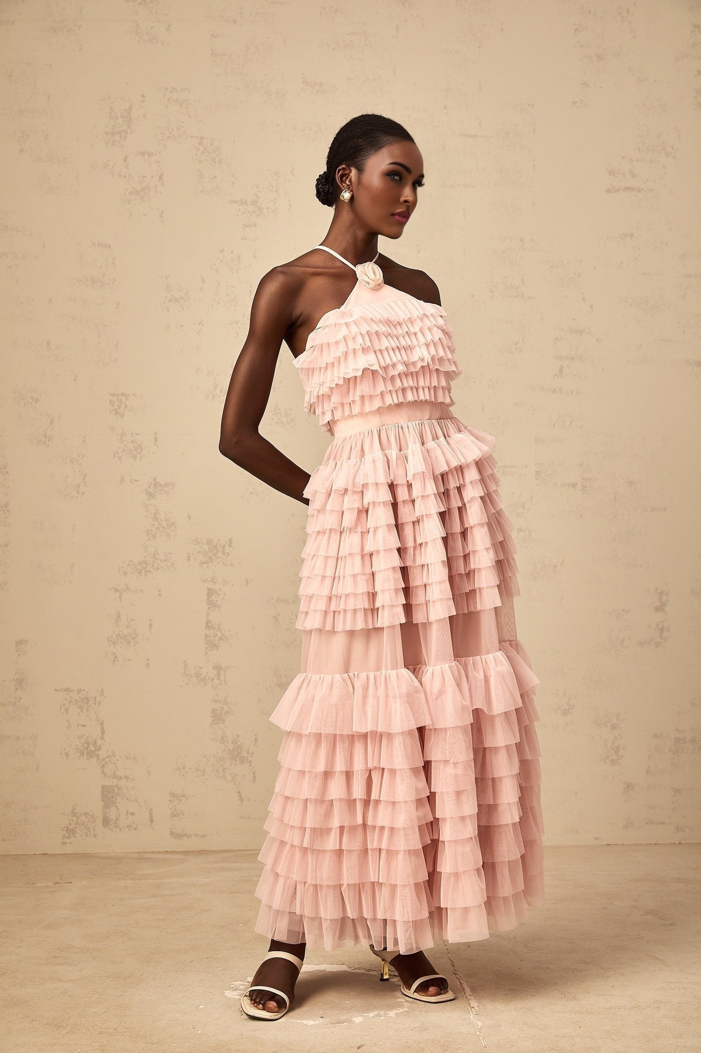 A pink maxi dress with ruffled tiered tulle skirt and floral petal brooch detail