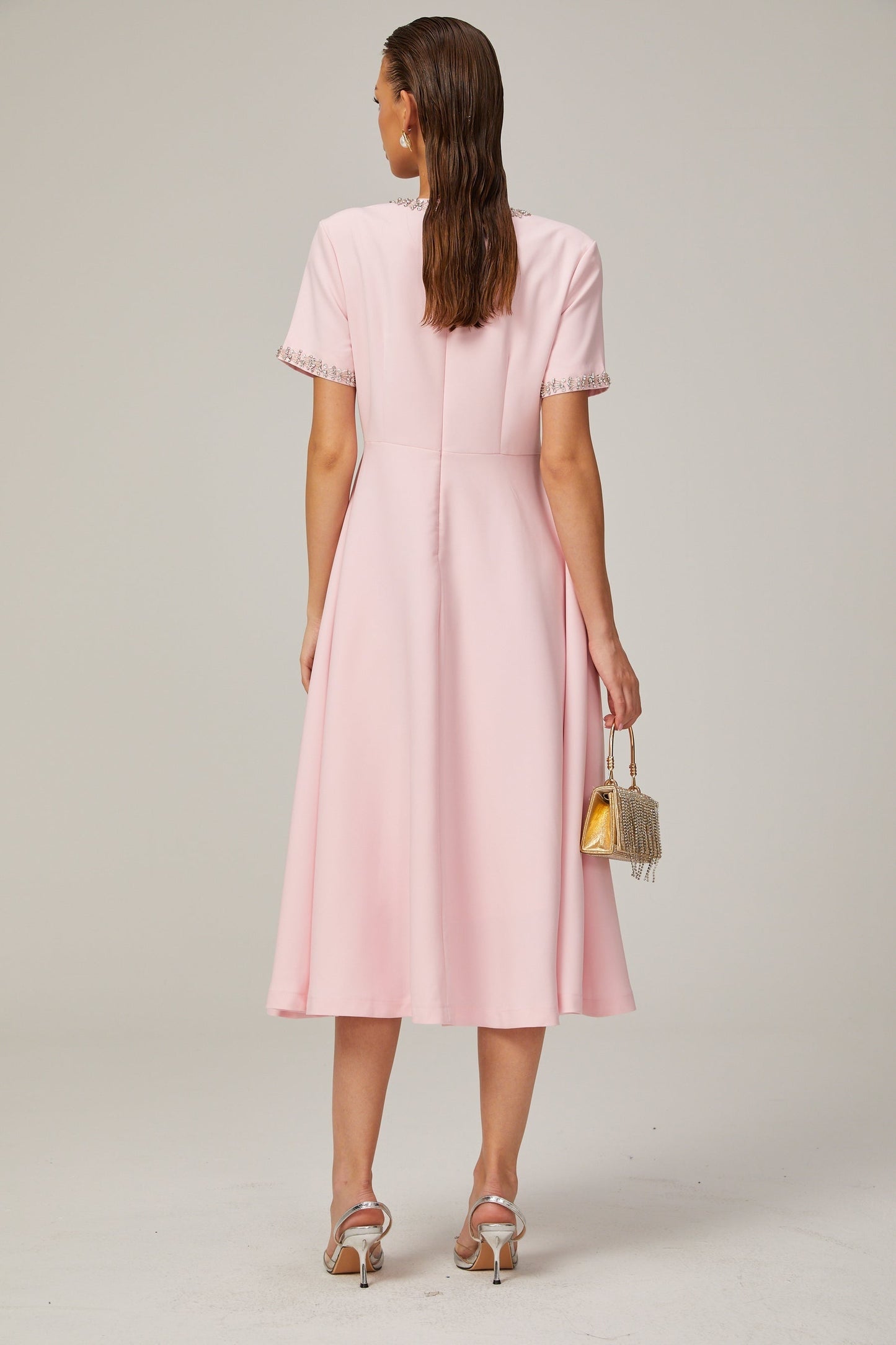 A pink midi dress with a crystalaccented bow and a Cassiopeiainspired design