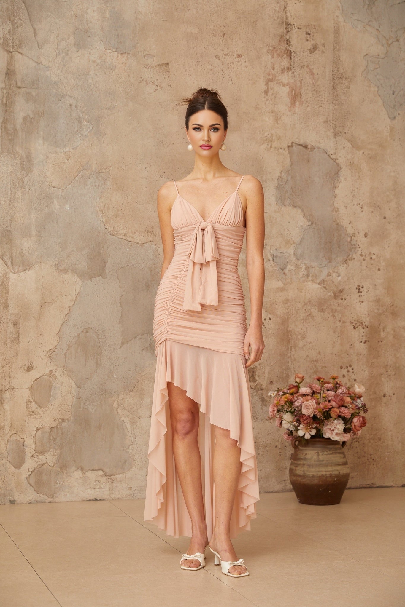 A pink midi dress with asymmetrical design and ruched detailing featuring a fitted silhouette and one shoulder neckline