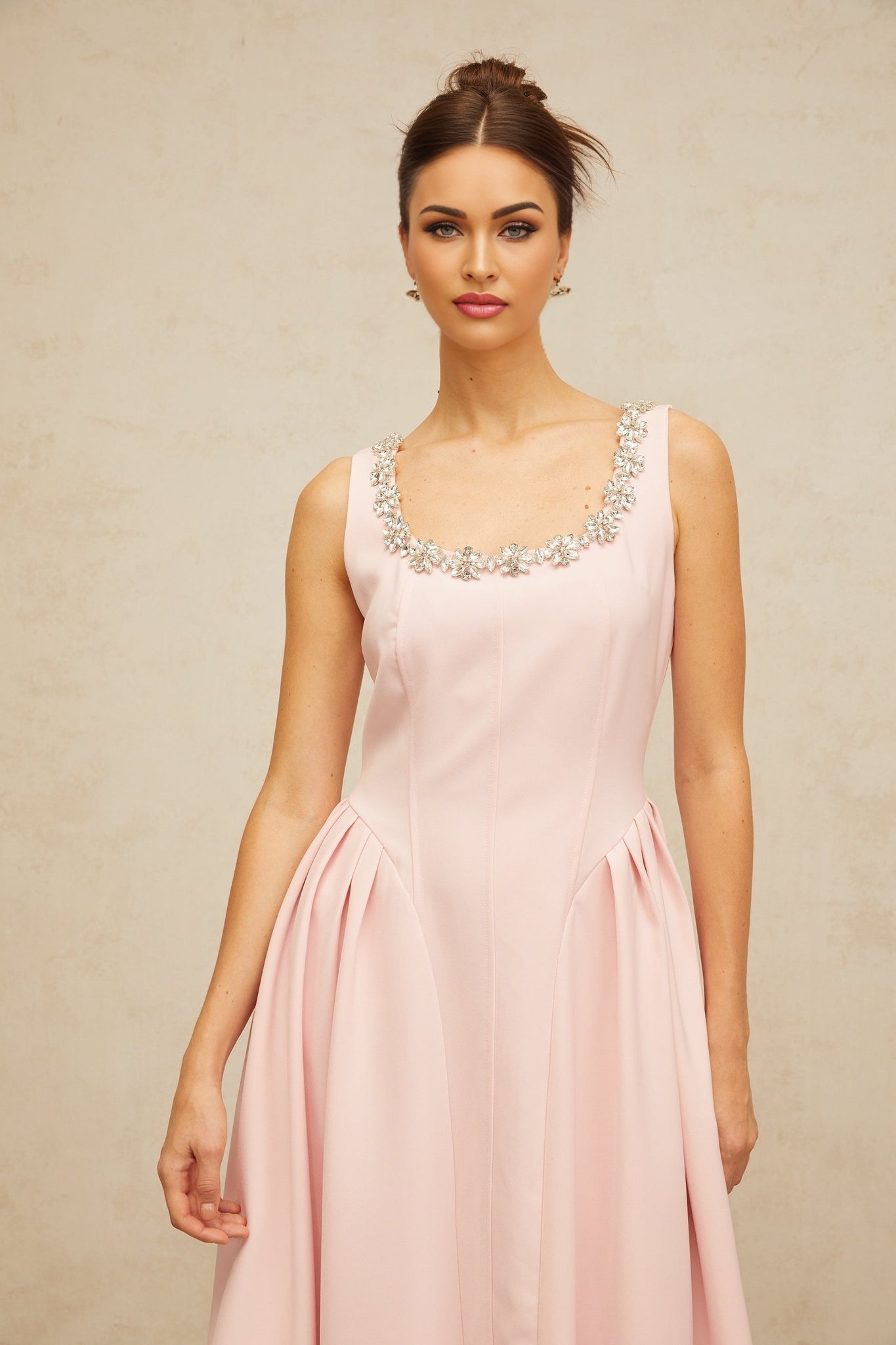 A pink midi dress with crystal embellishments and pleated details featuring a feminine silhouette and elegant design