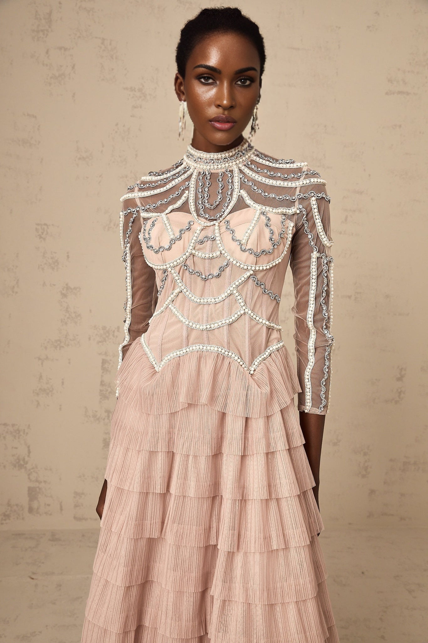 A pink tiered gown with beaded embellishments and semi sheer fabric