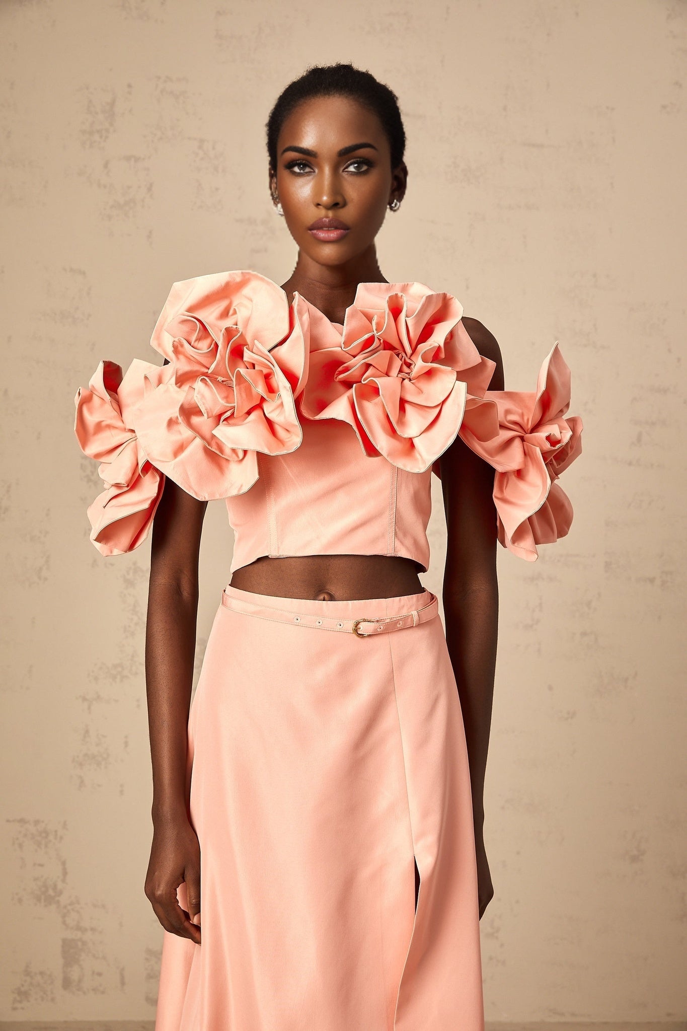 A pink twopiece outfit featuring a top and skirt with floral applique details matching set by Yvette