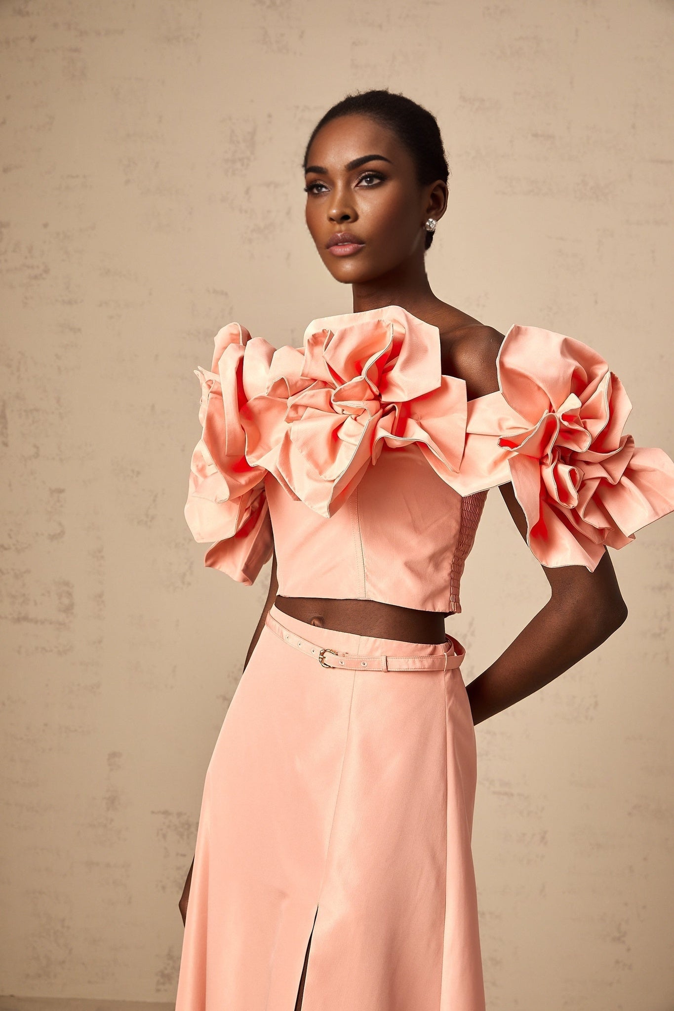 A pink twopiece outfit featuring a top and skirt with floral appliques creating a matching set for women