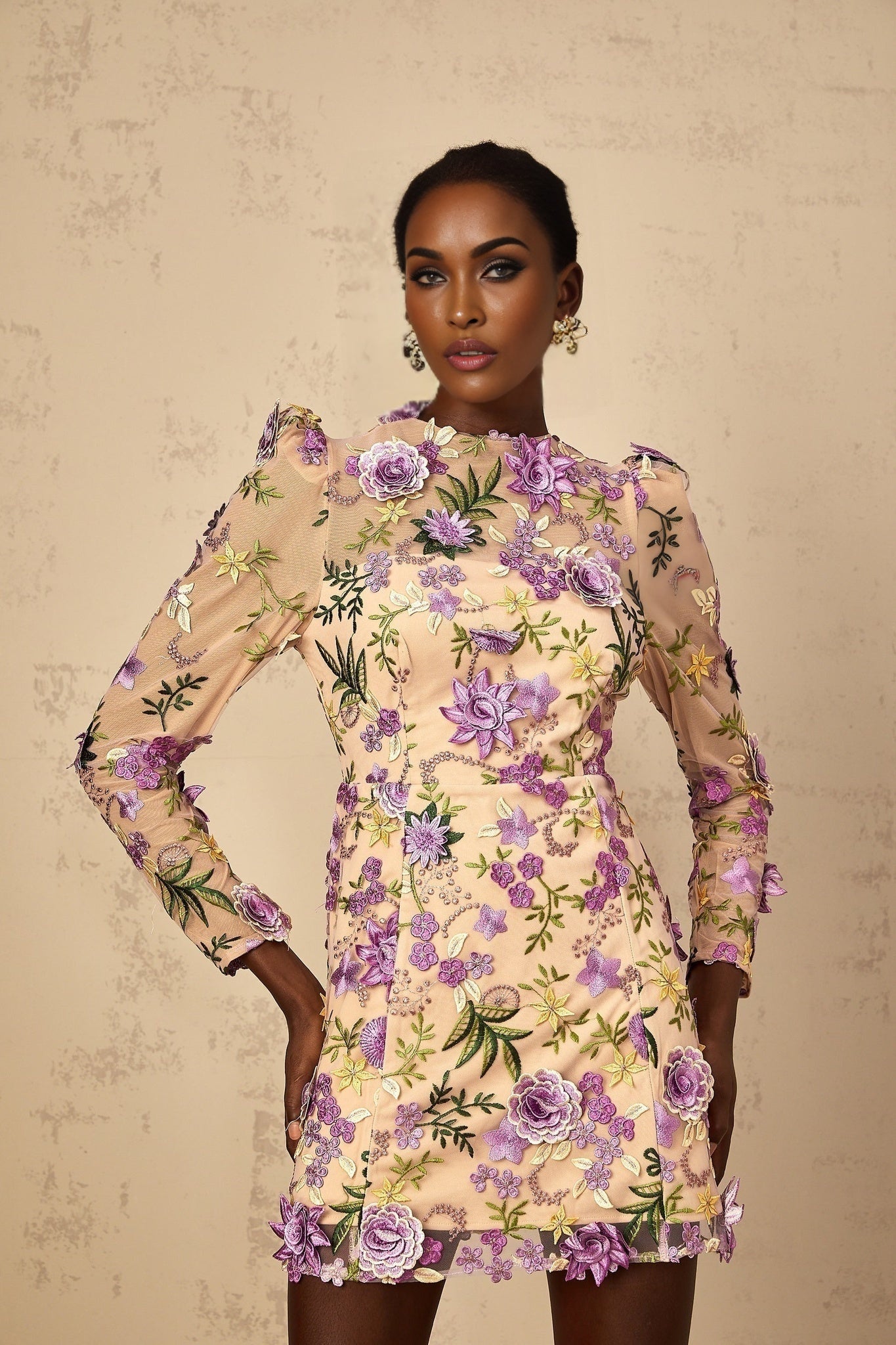 A purple mini dress with floral applique and embroidered tulle detailing featuring a short hemline and delicate floral patterns adorning the fabric