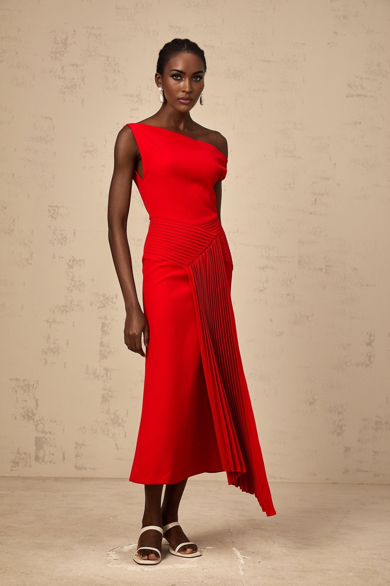 A red asymmetric draped midi dress with an uneven hemline and flowing fabric styled on a model against a plain background