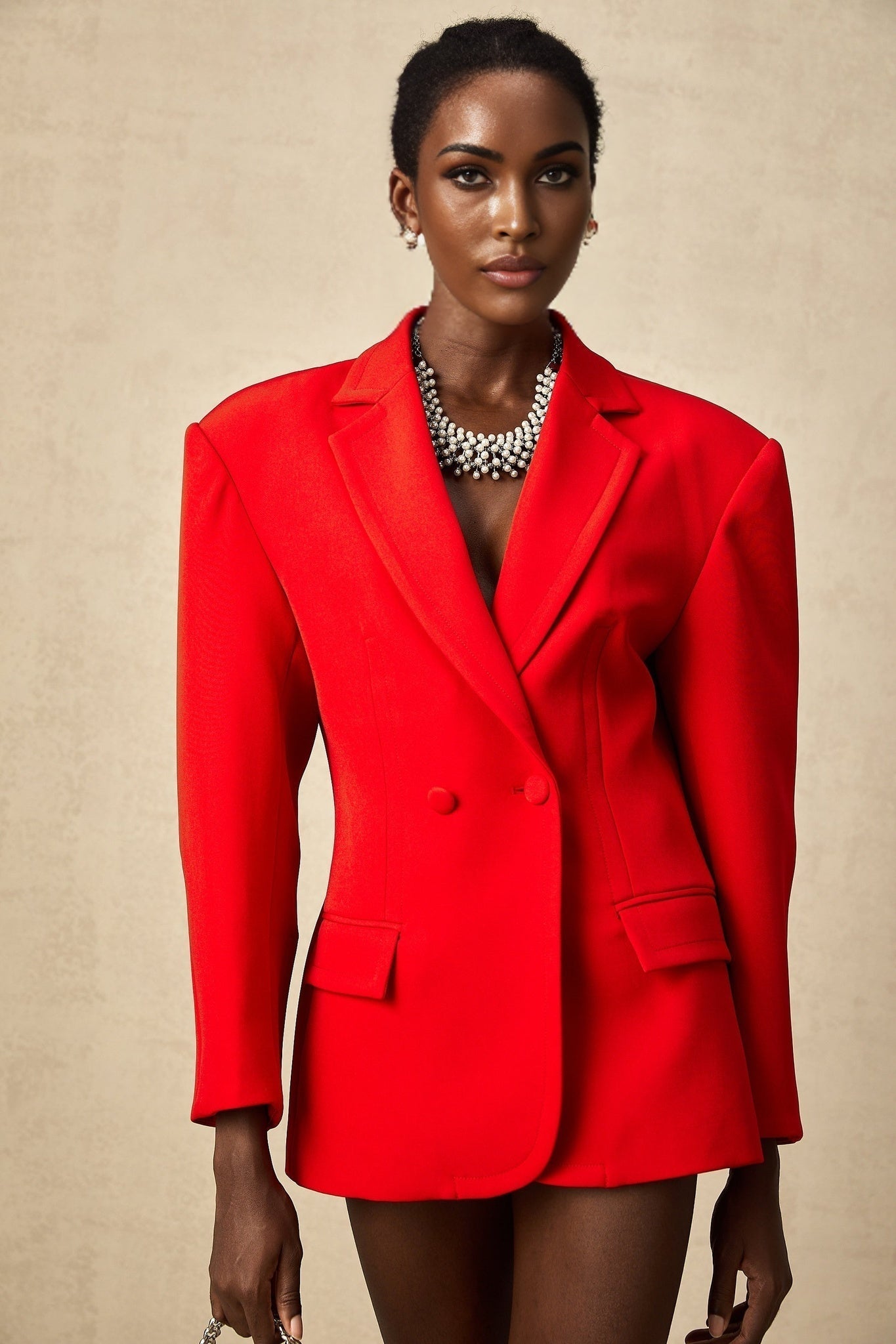 A red hourglass shaped blazer with double breasted buttons and a fitted waist creating a feminine silhouette