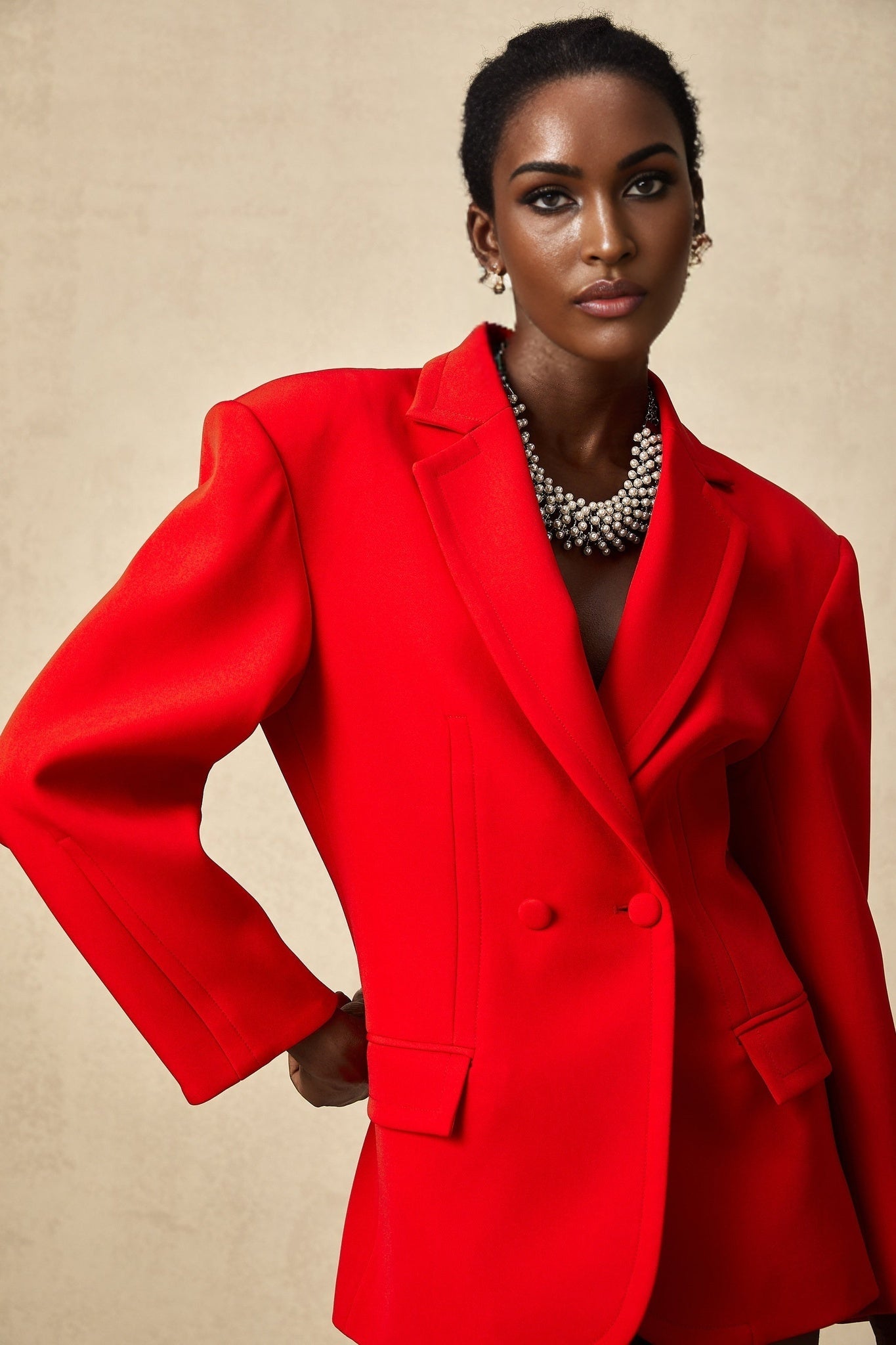A red hourglass shaped double breasted blazer from the brand Coline shown on a white background