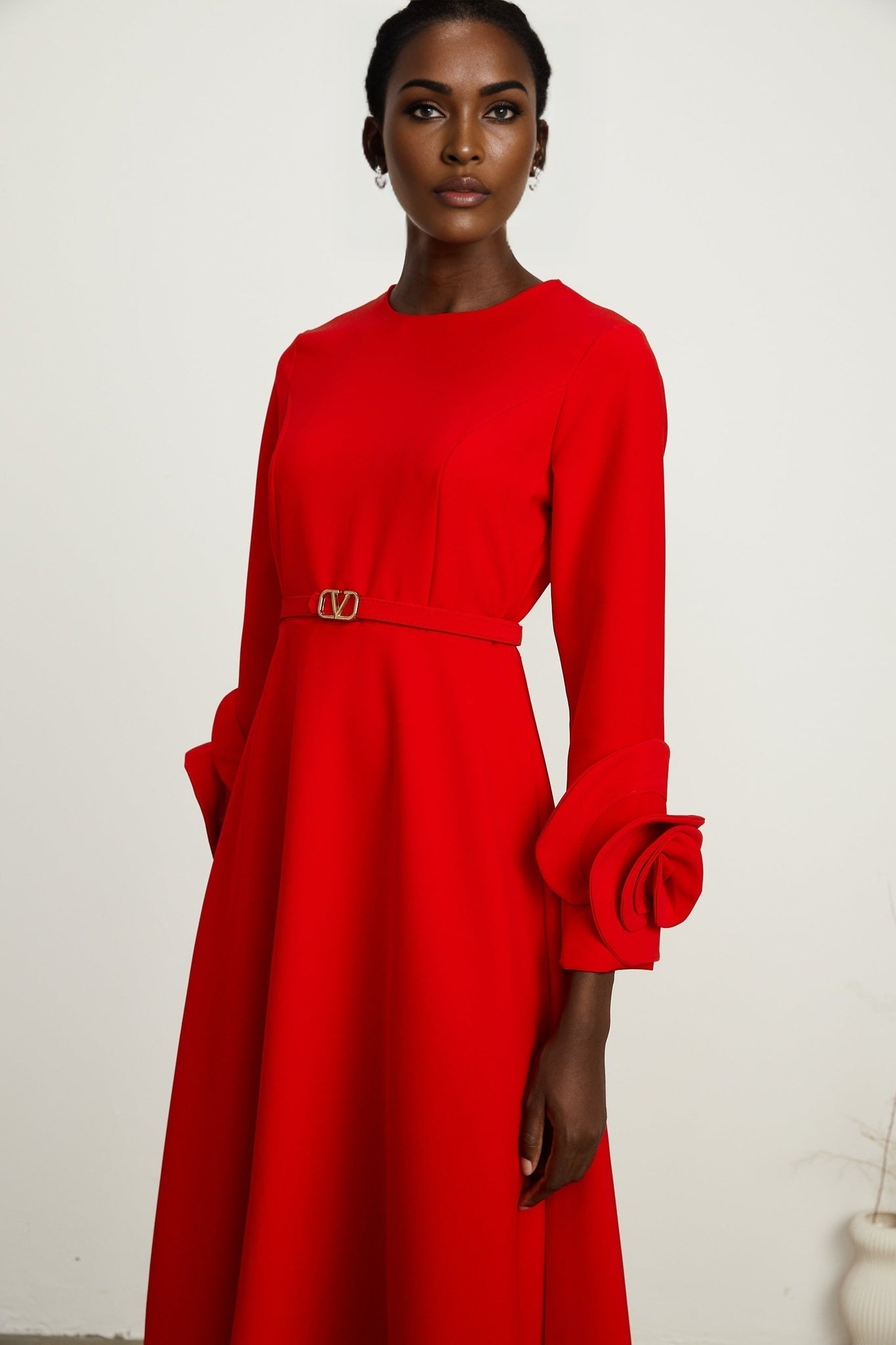 A red long sleeve dress with floral embellishments designed by Aurelia