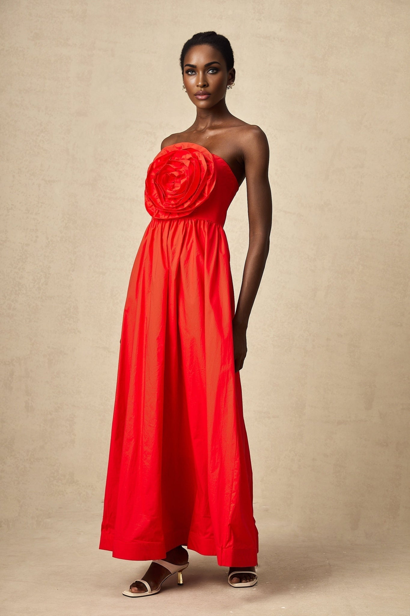 A red maxi dress with ruffled 3d petal details covering the bodice and skirt creating texture and visual interest
