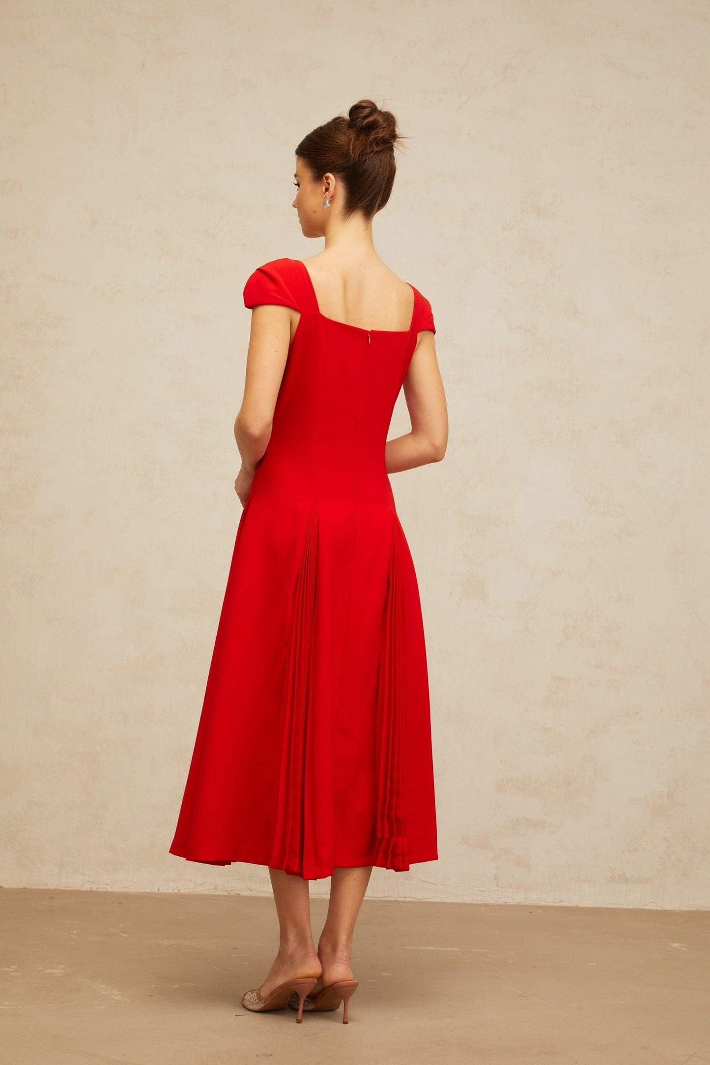 A red midi dress with a flared skirt and pleated details featuring a Gervaise design