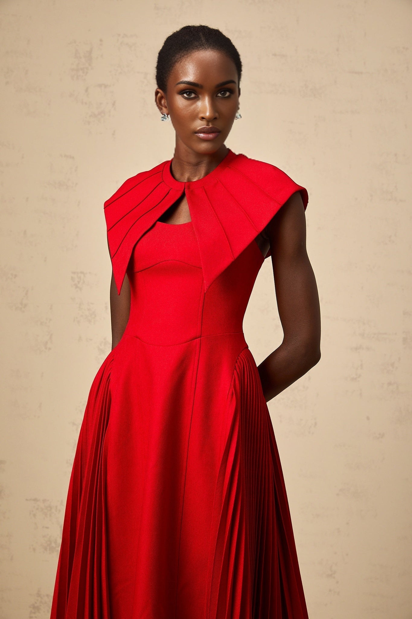 A red midi dress with capelike sleeves and pleated skirt featuring an Amaryllis design