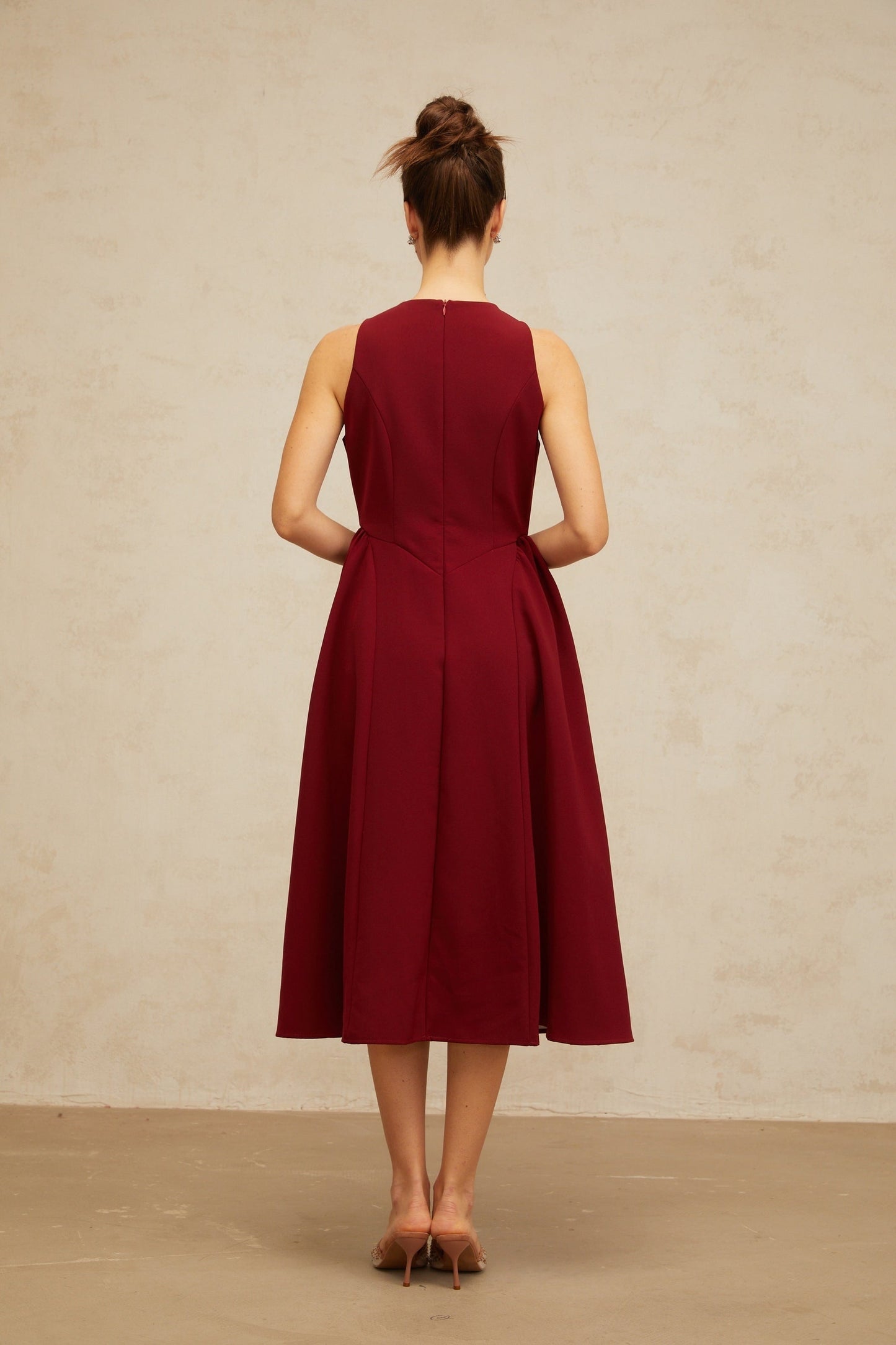 A red midi tank dress with a floral pattern featuring pleats and a fitted waist The dress has a vibrant flower motif throughout and falls to mid calf length