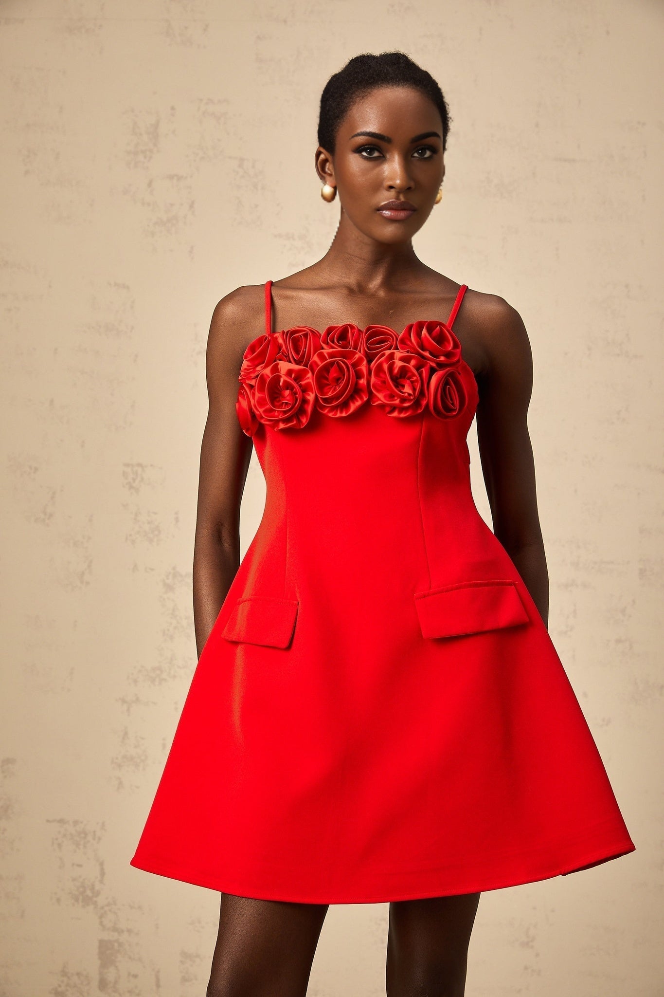 A red mini dress with a flared skirt featuring rose appliqués and a fitted bodice