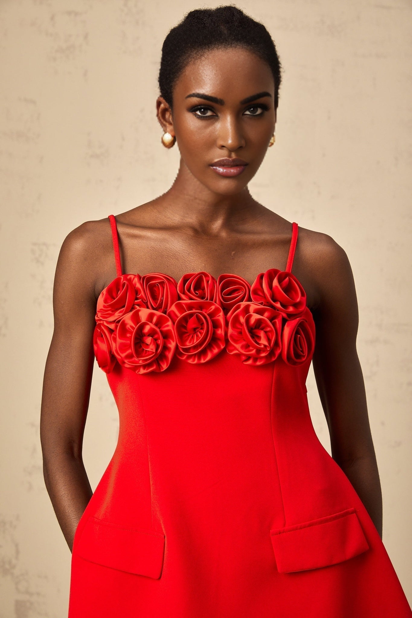 A red mini dress with a flared skirt featuring rose appliqués and a fitted bodice