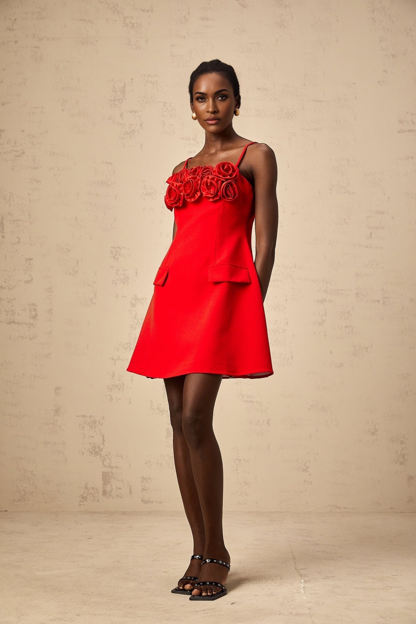 A red mini dress with a flared skirt featuring rose appliqués and a fitted bodice